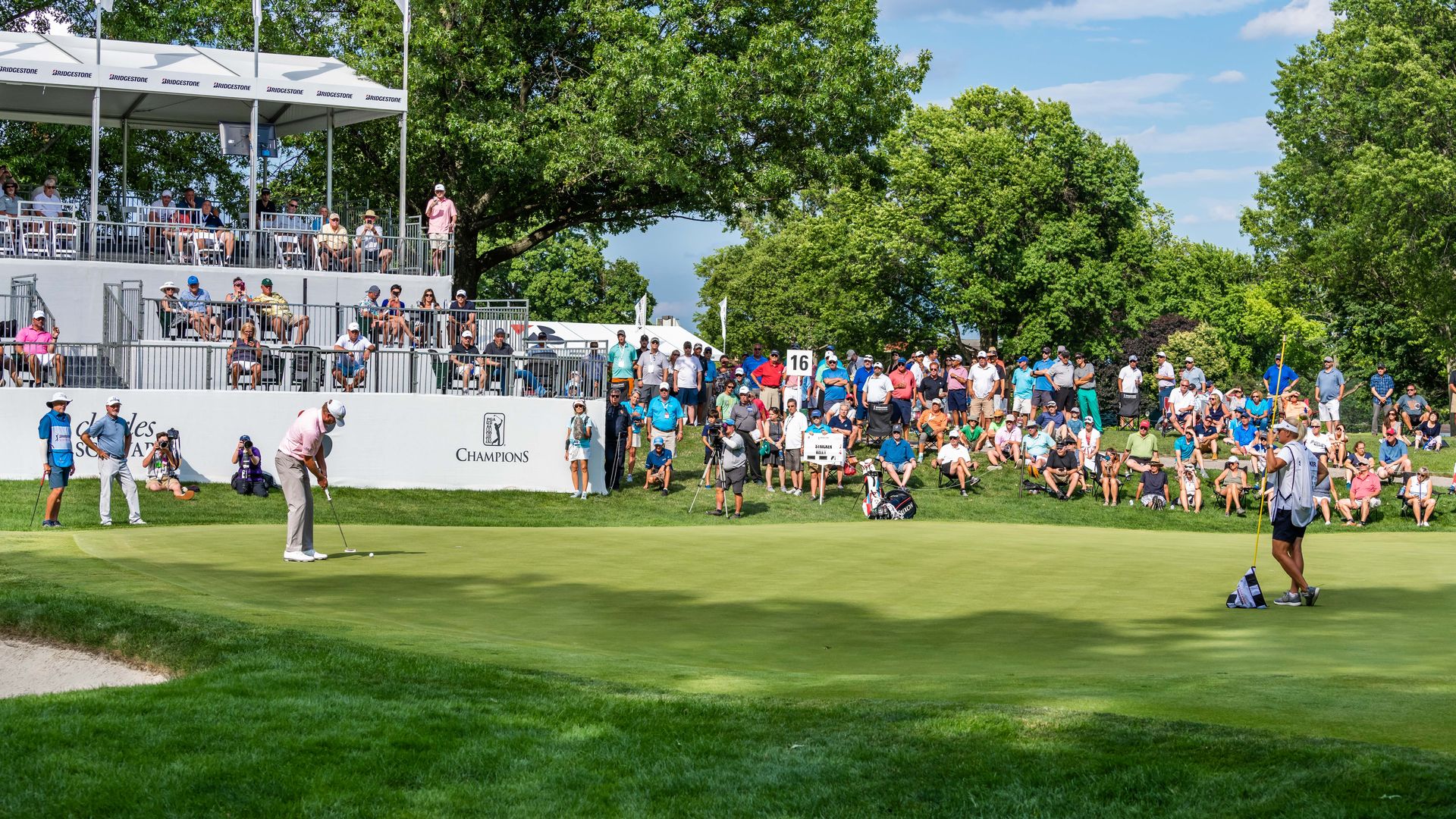 Steve Stricker putts on the 16th green at Firestone Country Club with fans looking on.