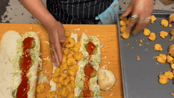 A gif of a person stuffing a fully-dressed shrimp poboy and then folding it closed.