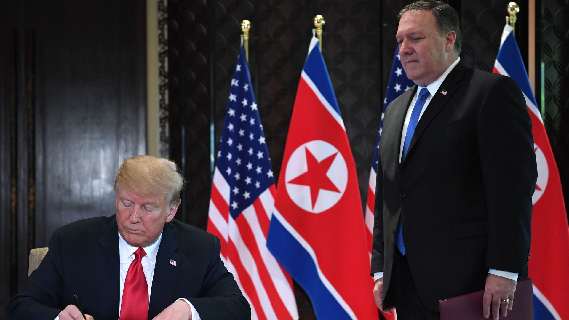 Donad Trump signing something while Secretary of State Mike Pompeo watches