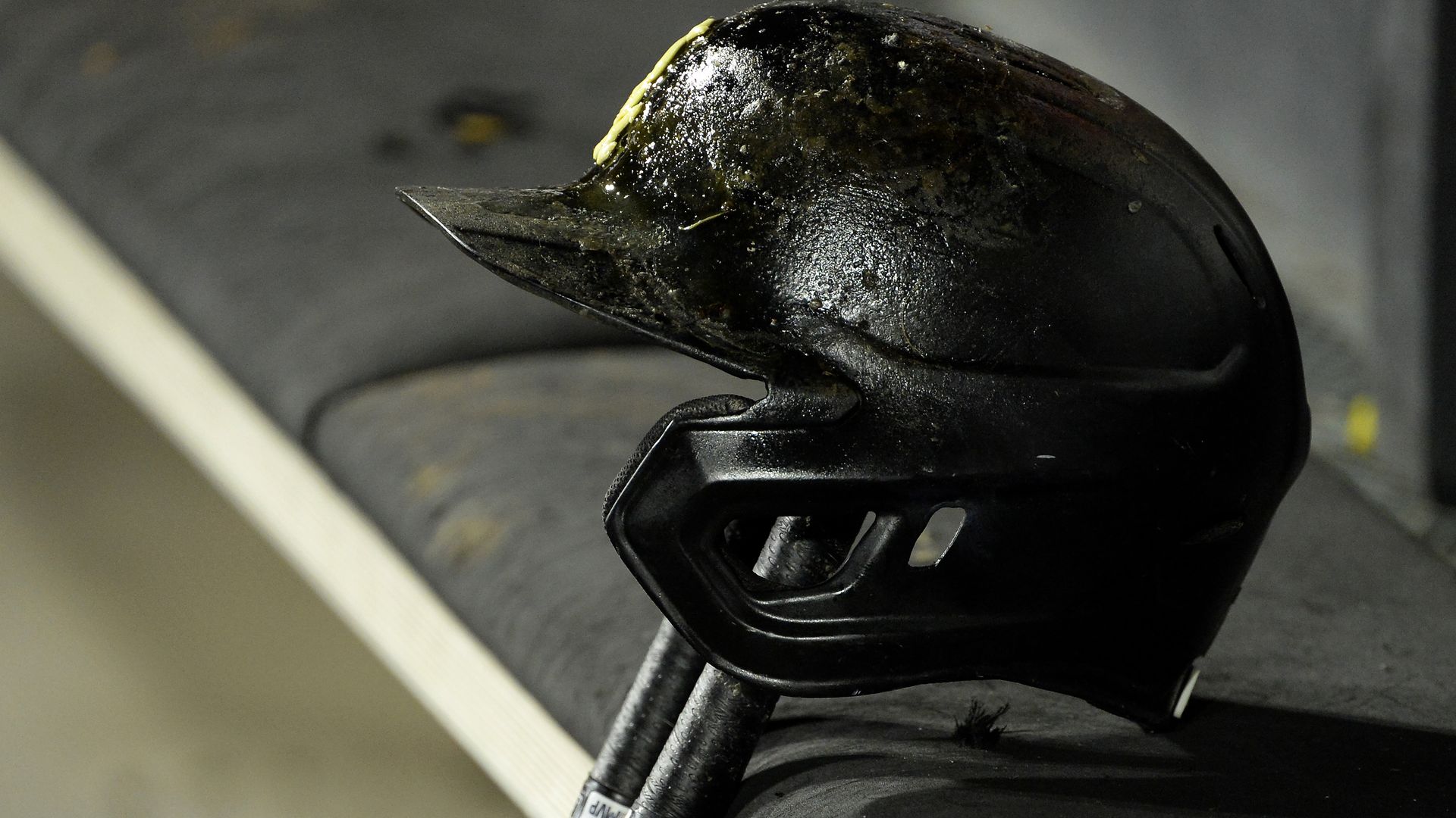A baseball batting helmet resting on a bat.