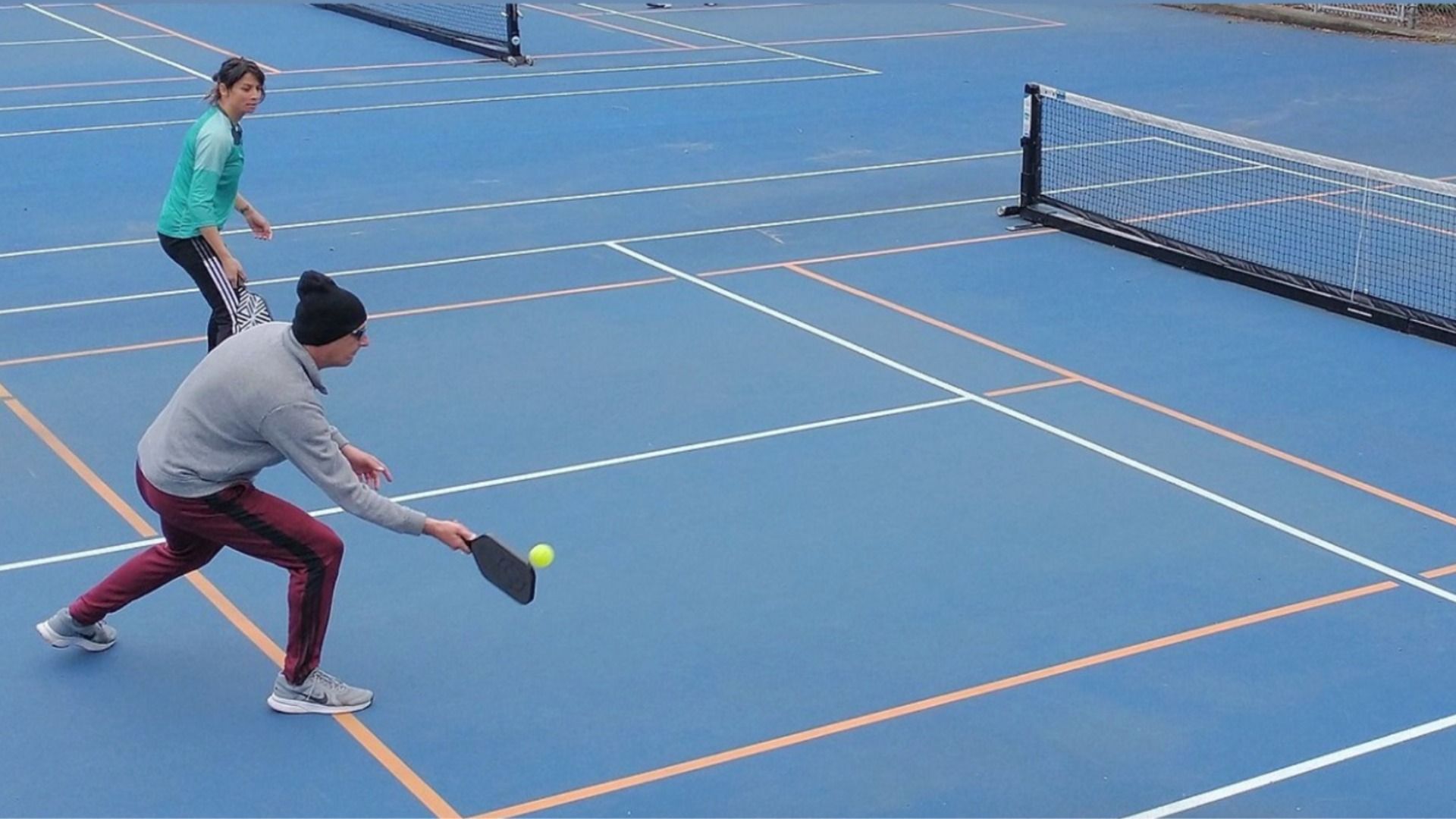 A pickleball player strikes the ball during a match on a Seattle parks court.