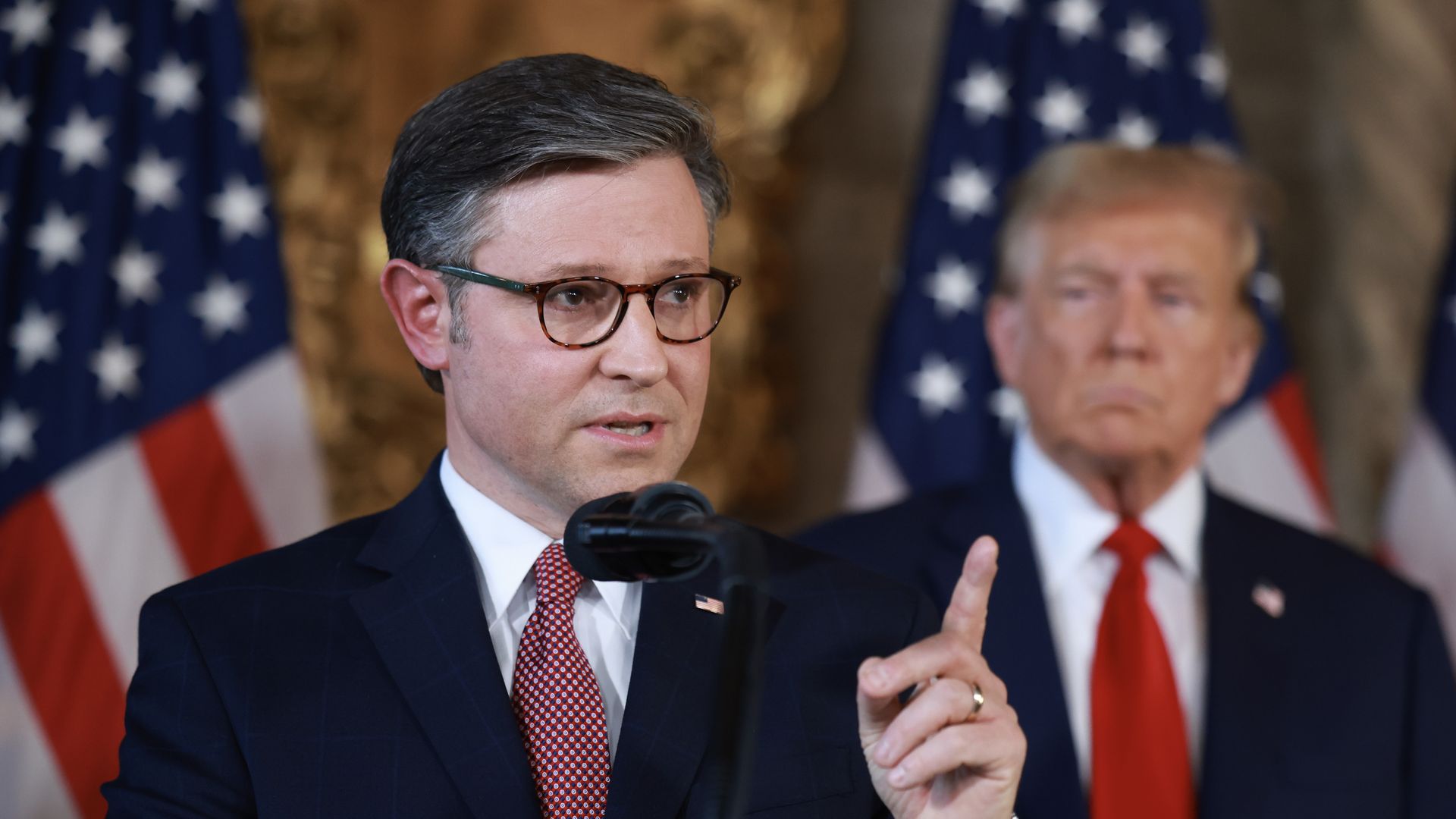 Mike Johnson at podium with former President Trump in background