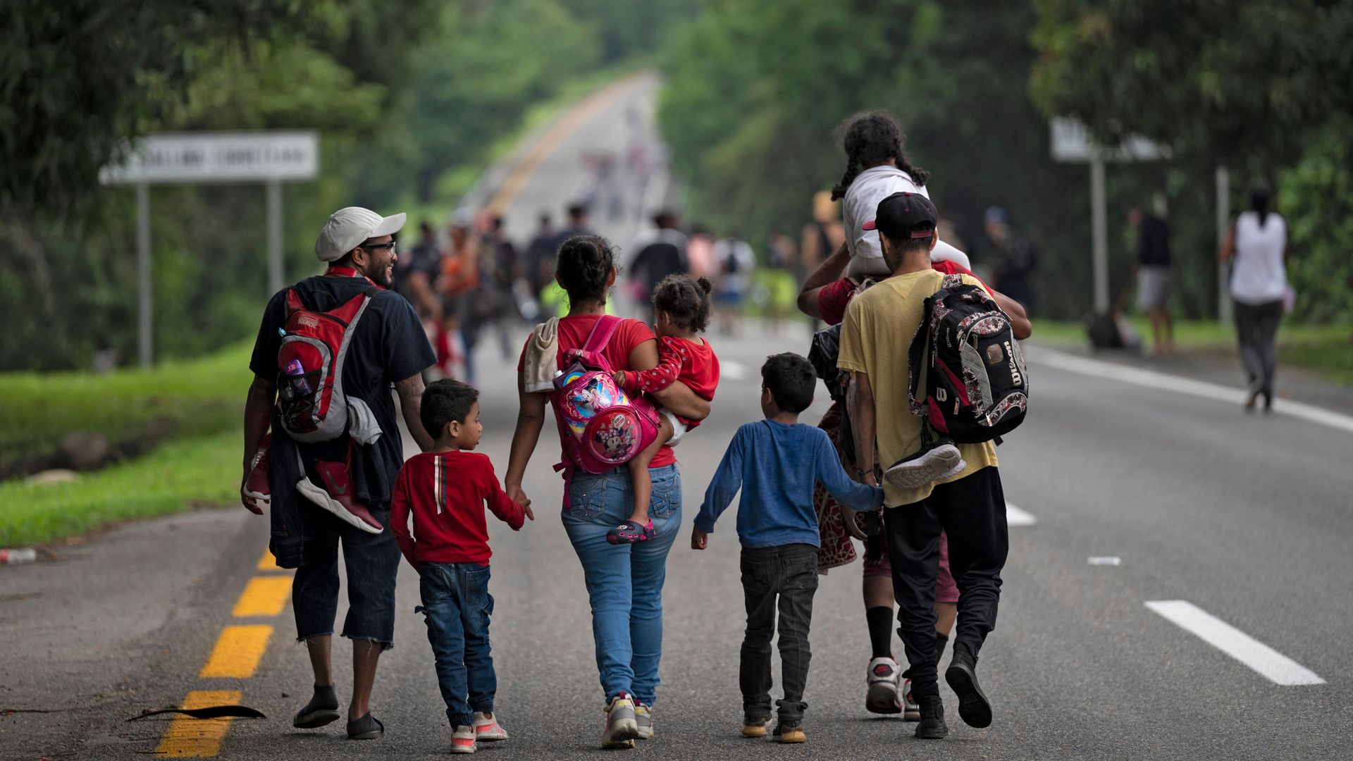 A family of migrants walking on a road