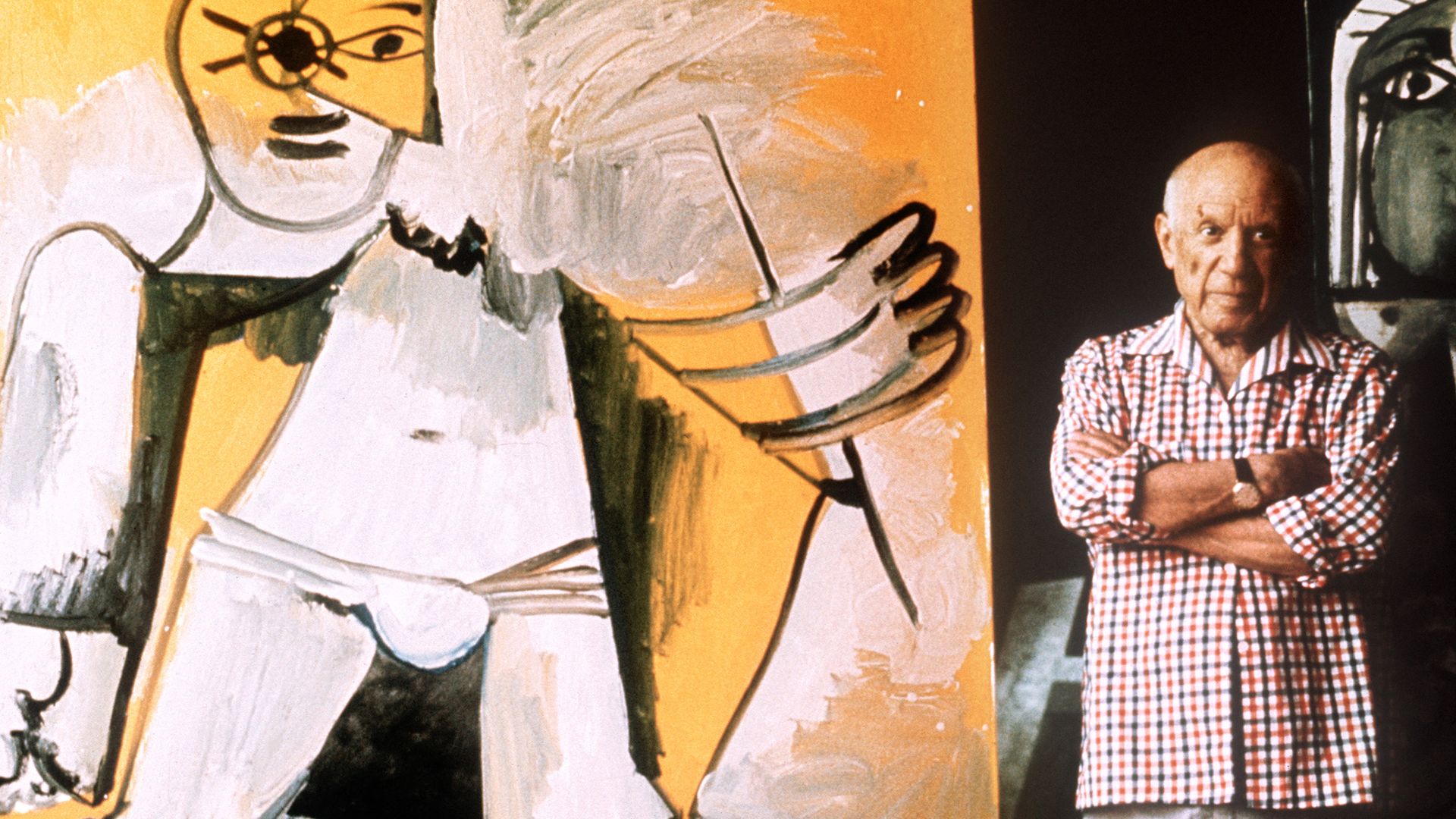 Famed painter Pablo Picasso stands next to one of his works. 