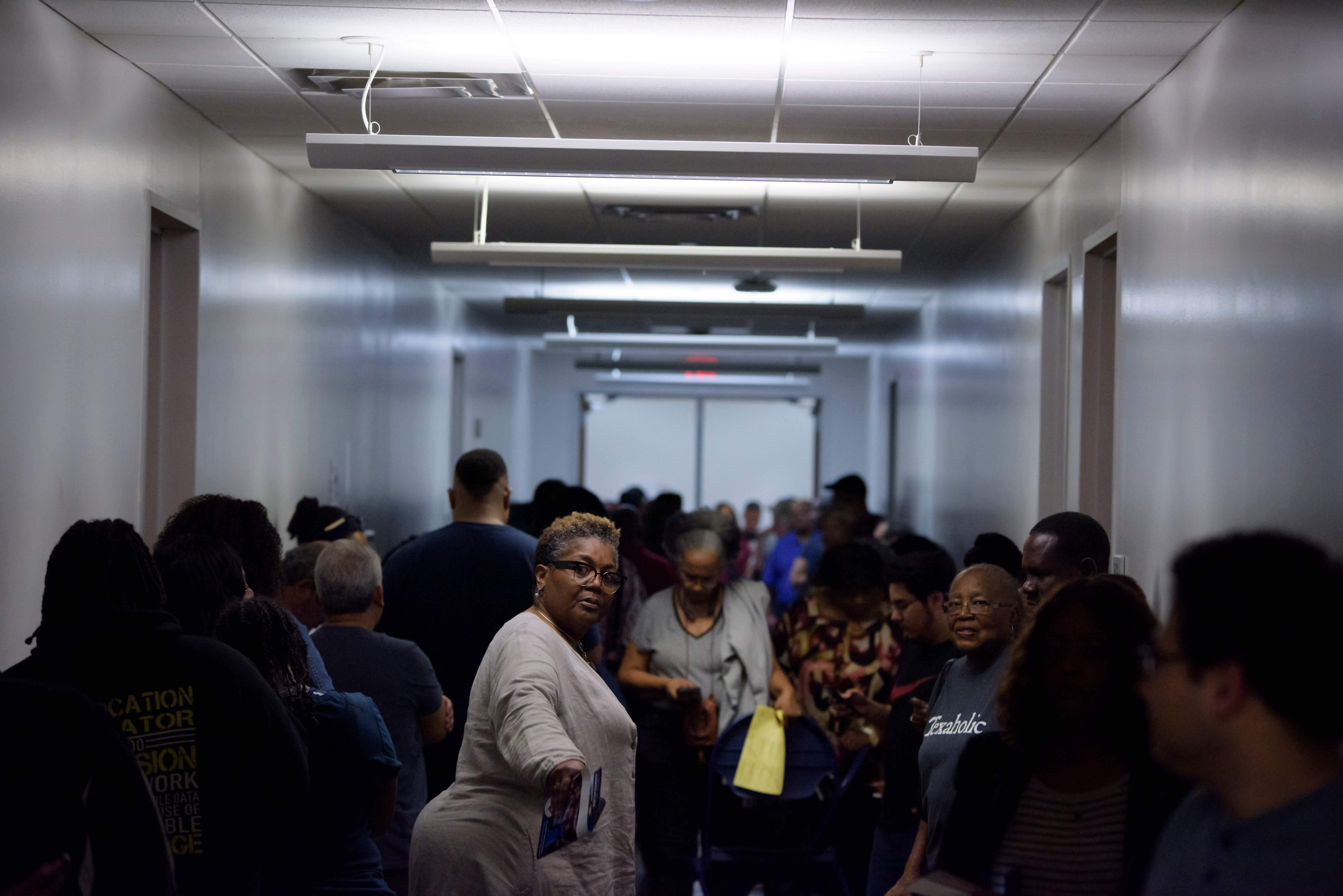 In this image, a crowd of people stand in a hallway to vote