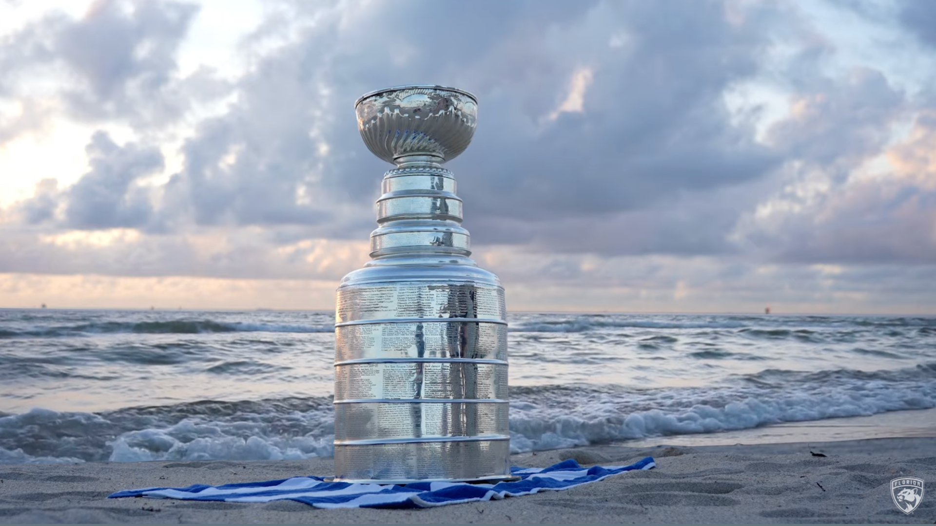 A screenshot from YouTube of the Stanley Cup on a beach blanket next to the ocean.