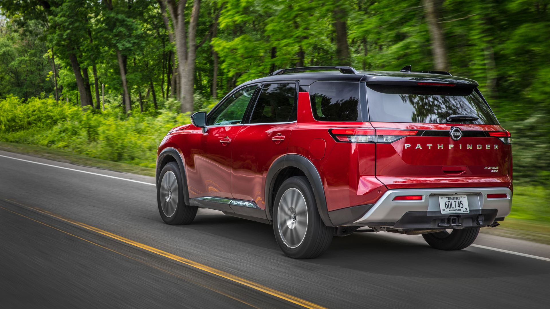 Image of a red 2022 Nissan Pathfinder SUV on a country road. 