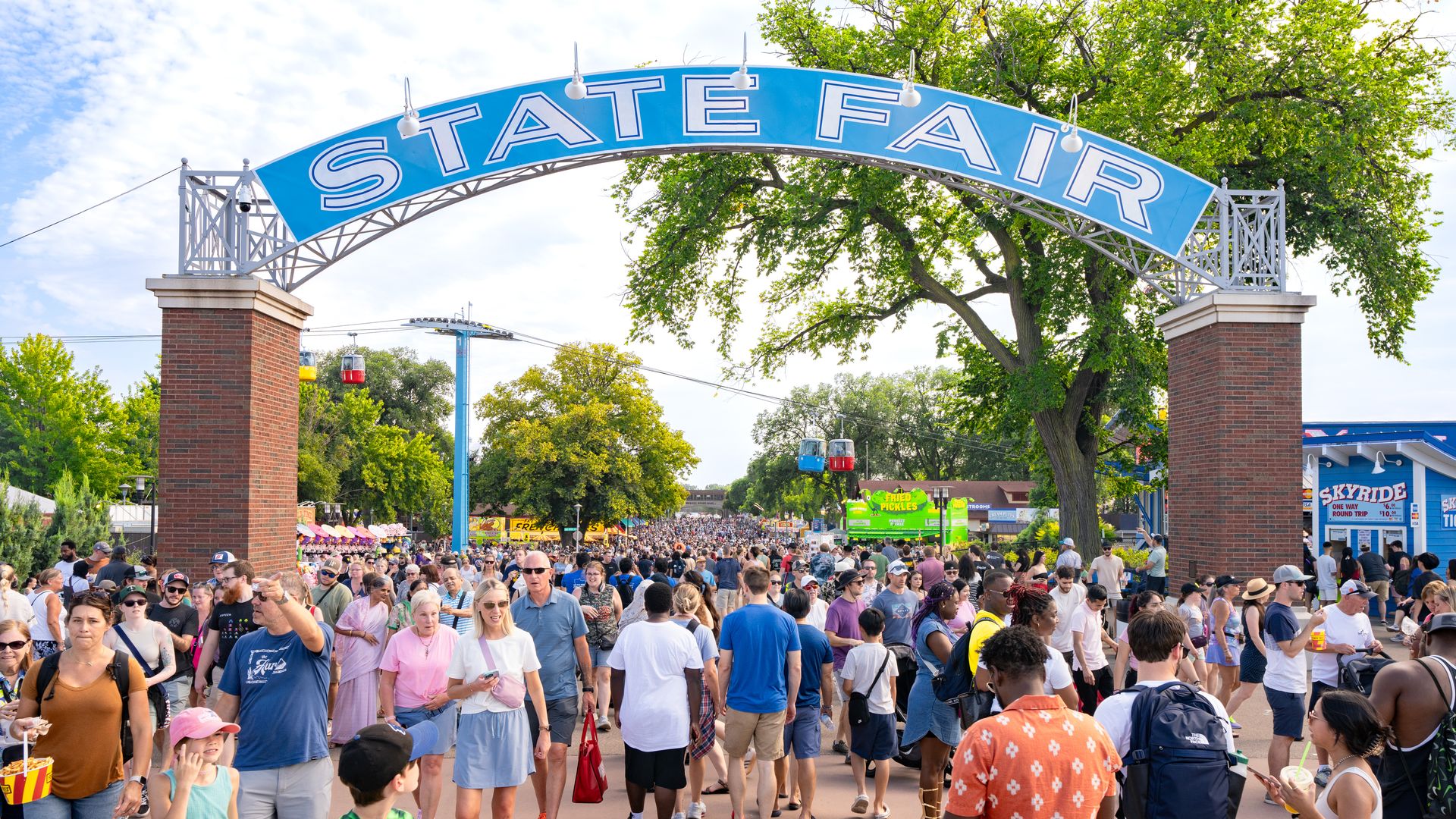 People walking under the blue State Fair arch