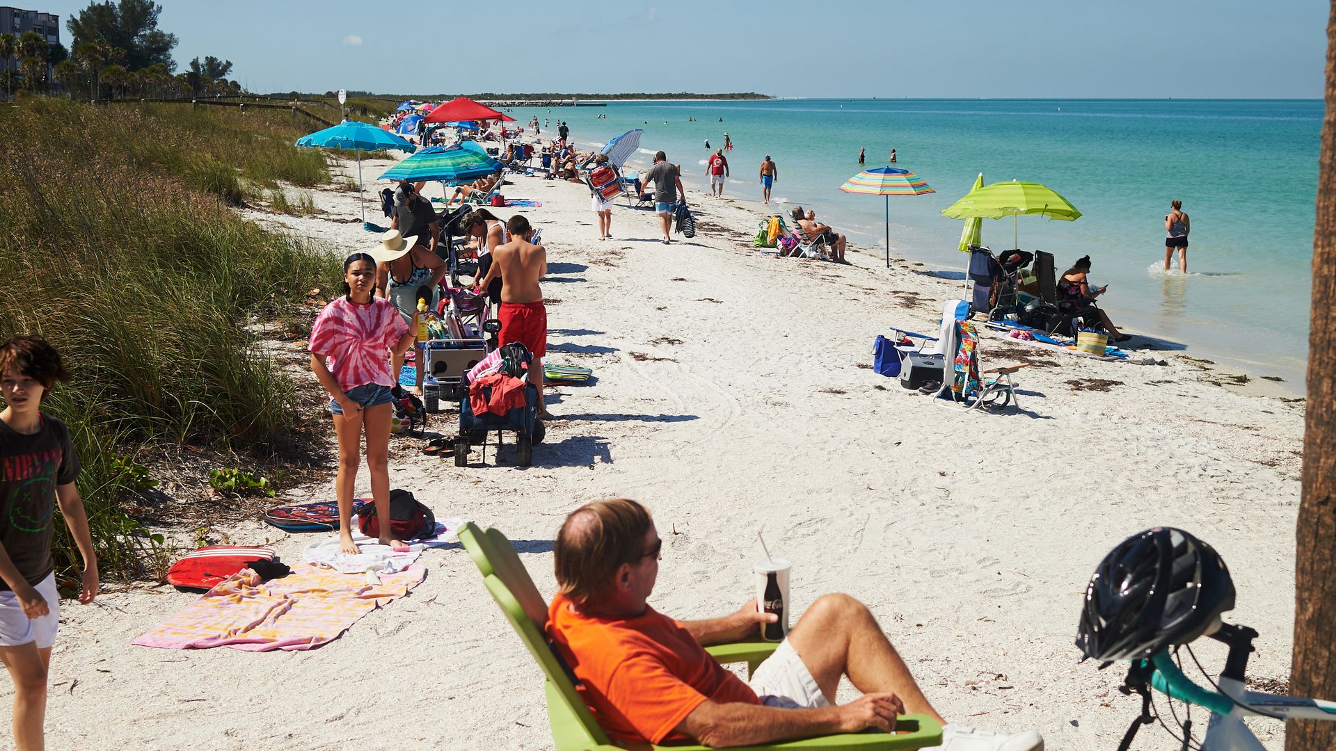People sit in the sand at Pass-A-Grille beach.