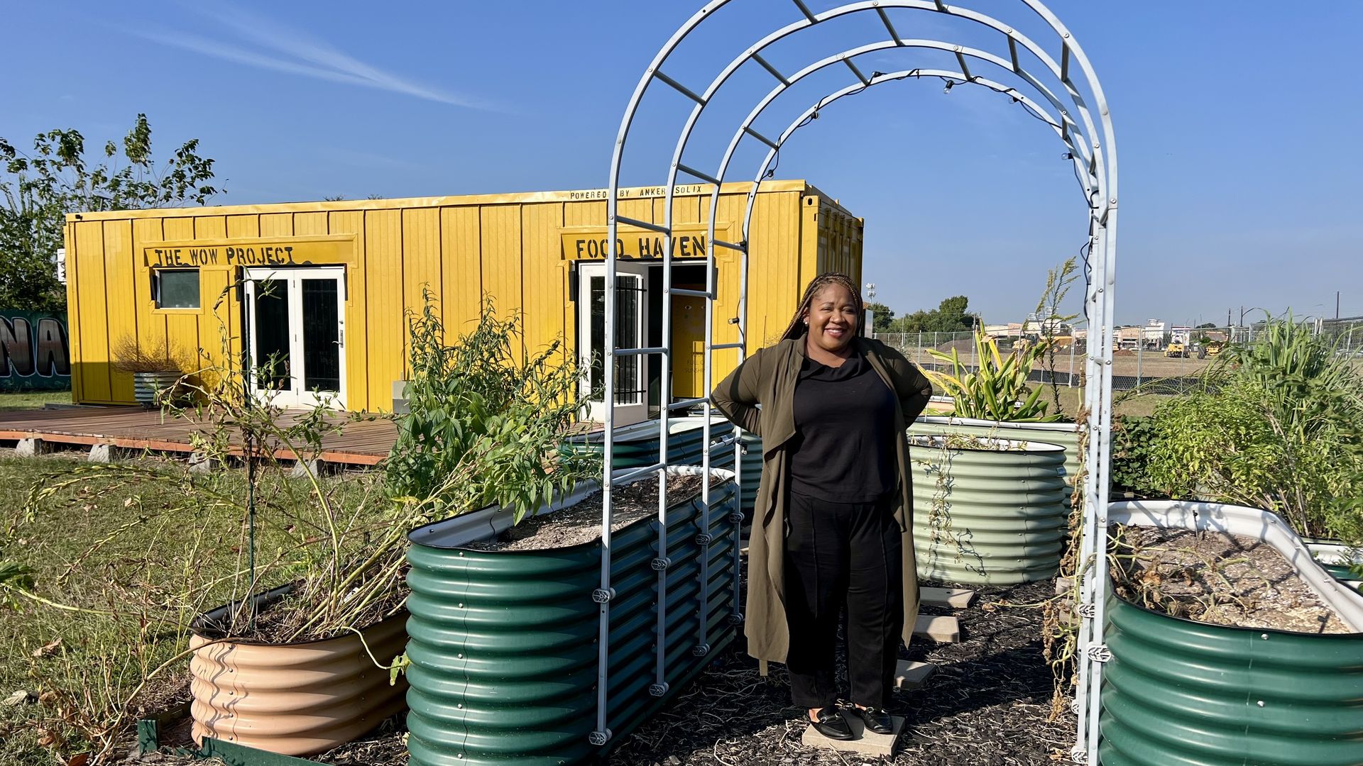 A photo of a woman in front of a raised garden and a yellow container box. 