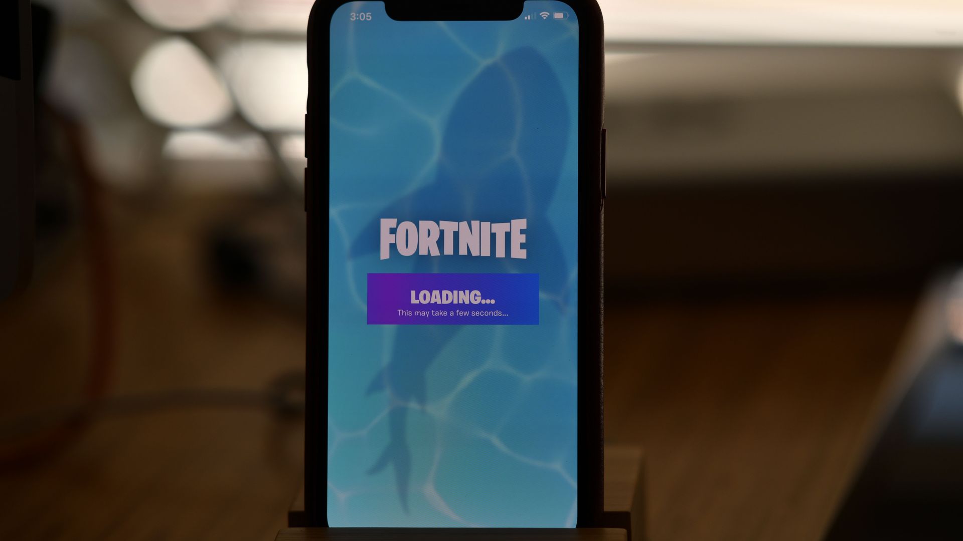 A photo of an iPhone displaying a loading screen for Epic Games' Fortnite app.