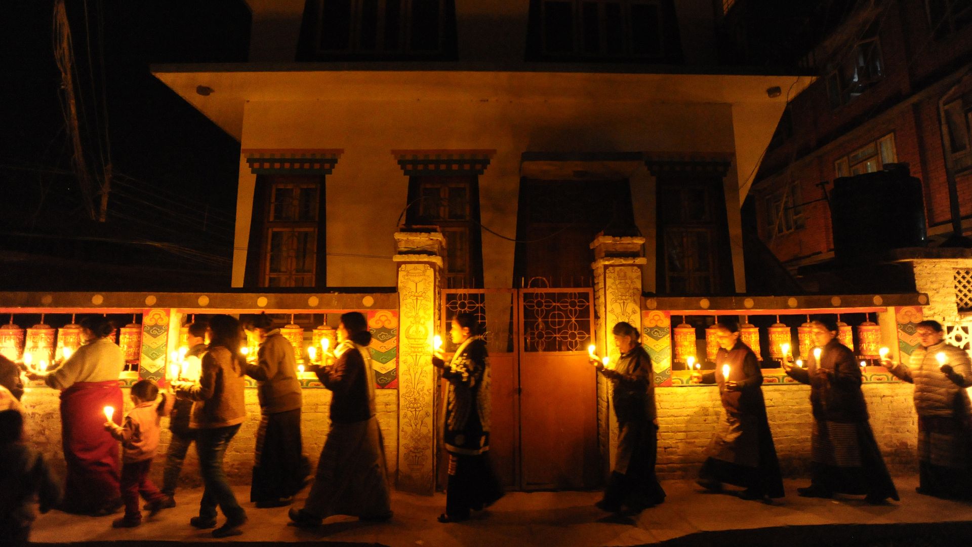 People walk around a temple with candles