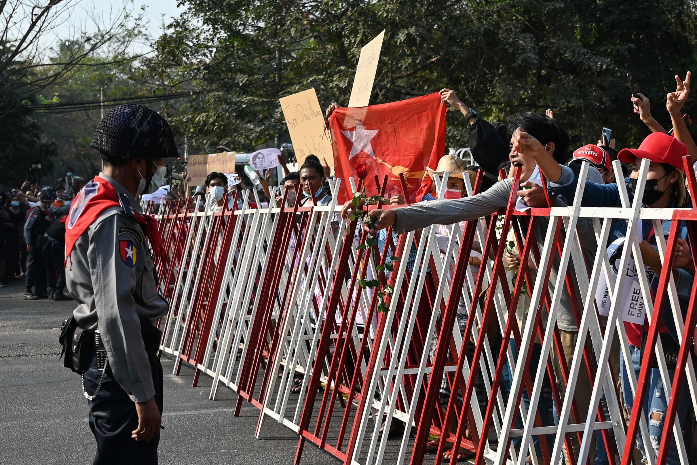 A protester at a barricade hands a rose to a police officer during a demonstration against the military coup in Yangon. 