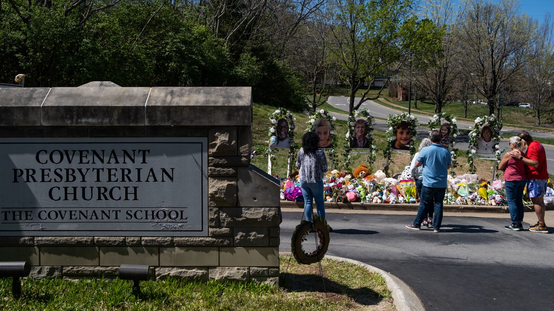 People visit a makeshift memorial at the entrance of The Covenant School