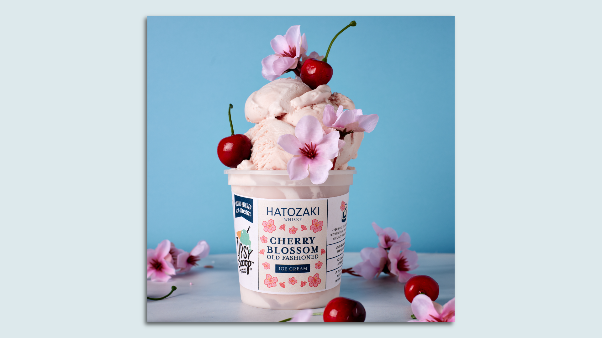 A pint of cherry ice cream with cherries and cherry blossoms on top 