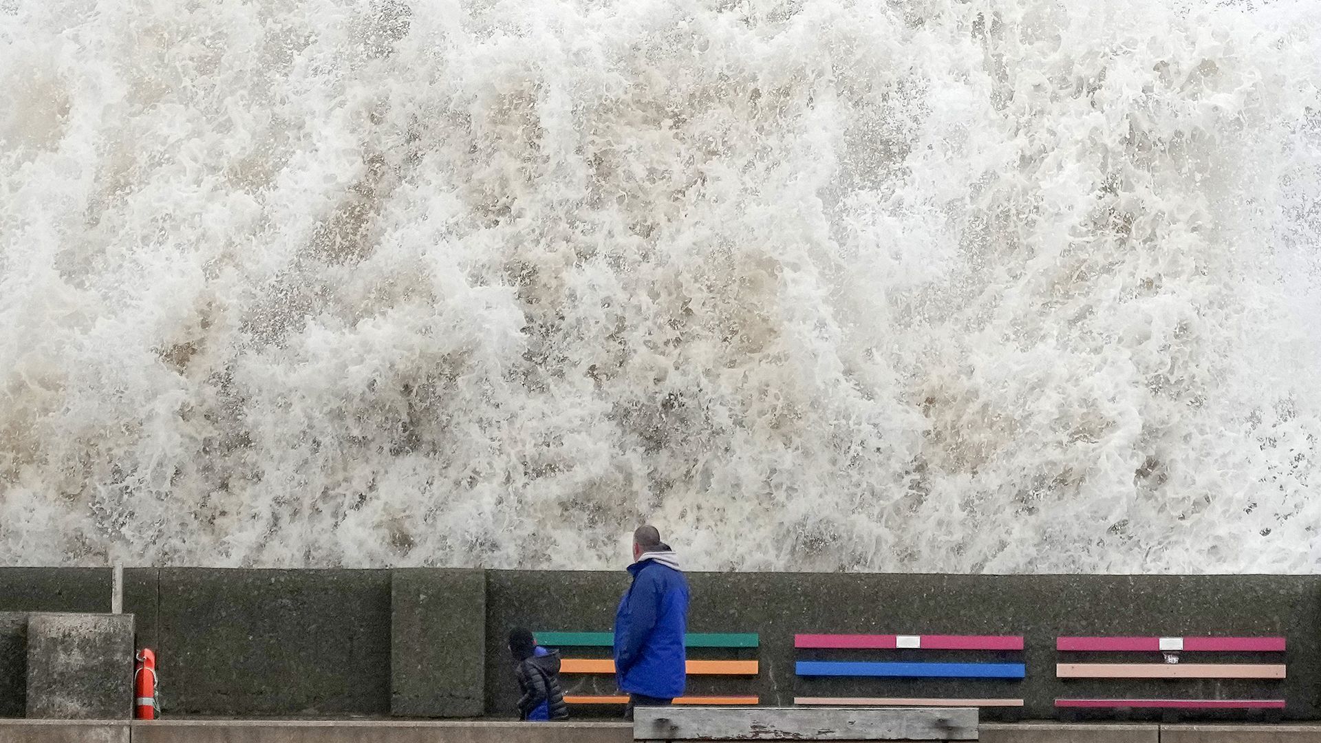 People view the waves created by high winds and spring tides hitting the sea wall at New Brighton promenade on February 17, 2022 in Liverpool, England.