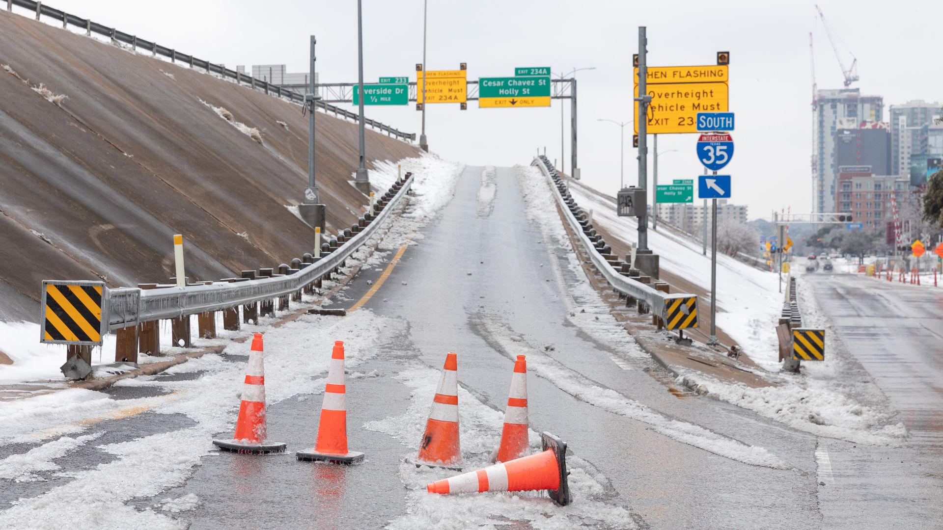 A photo of a frozen road with cones lined in front of it.