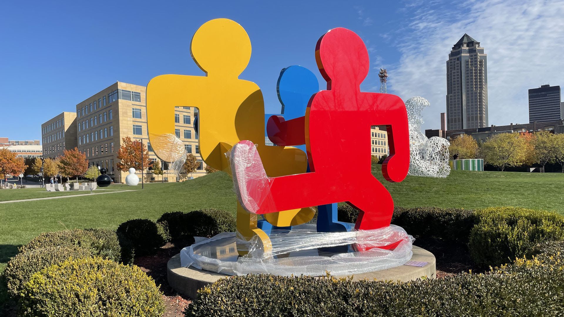 Three figure sculptures of yellow, blue and red as part of "Untitled (Three Dancing Figures, Version C)" at the Pappajohn Sculpture Park.