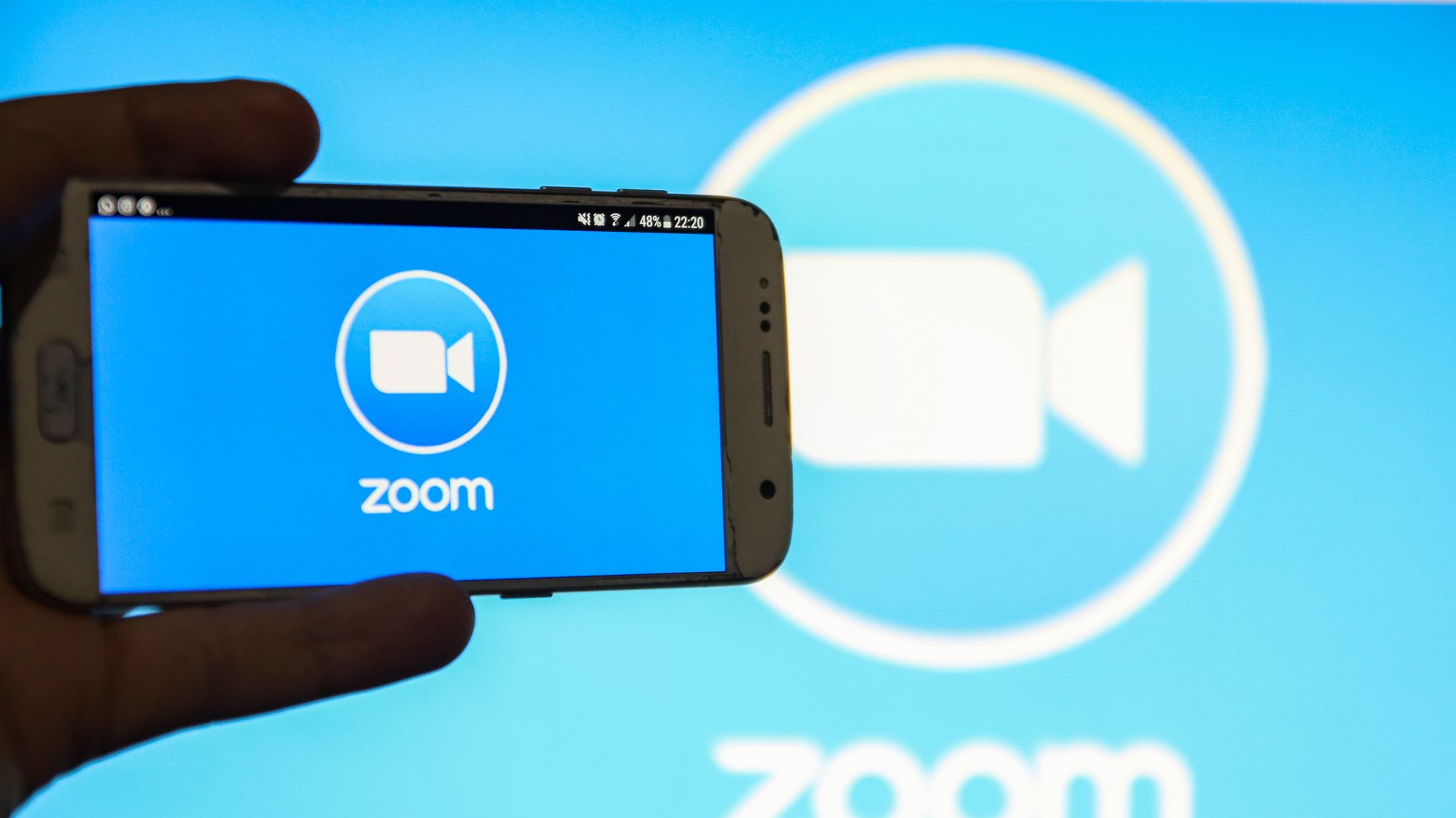 A phone and a background with the Zoom logo