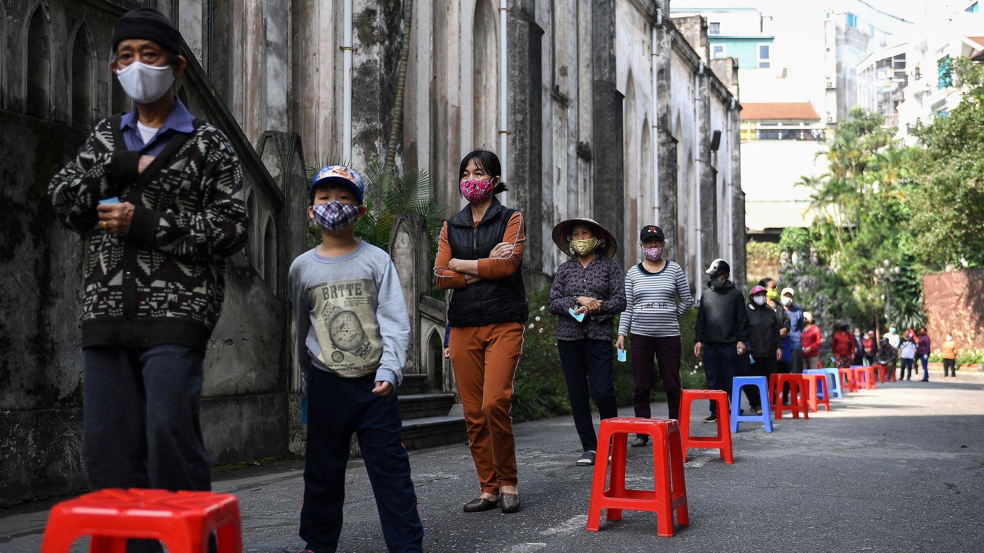 People wait in line for free rice in Hanoi.