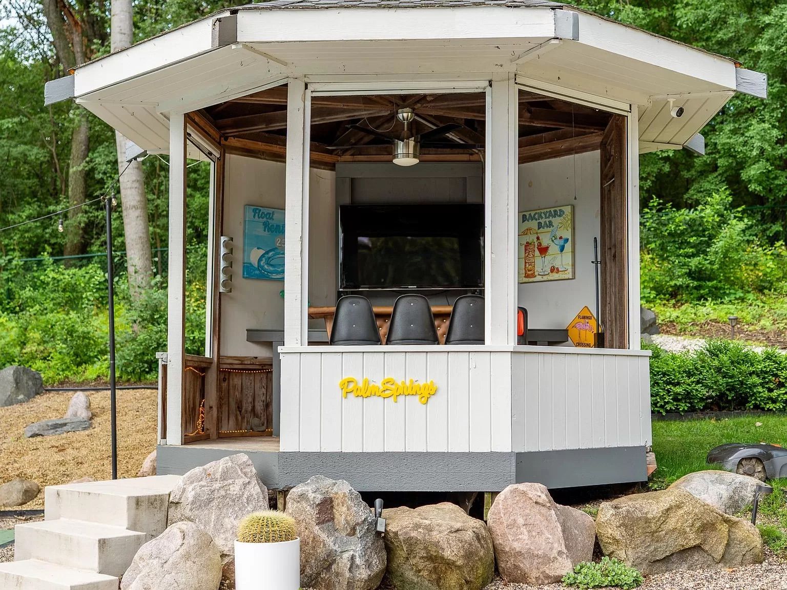 A gazebo with a tv and three chairs.
