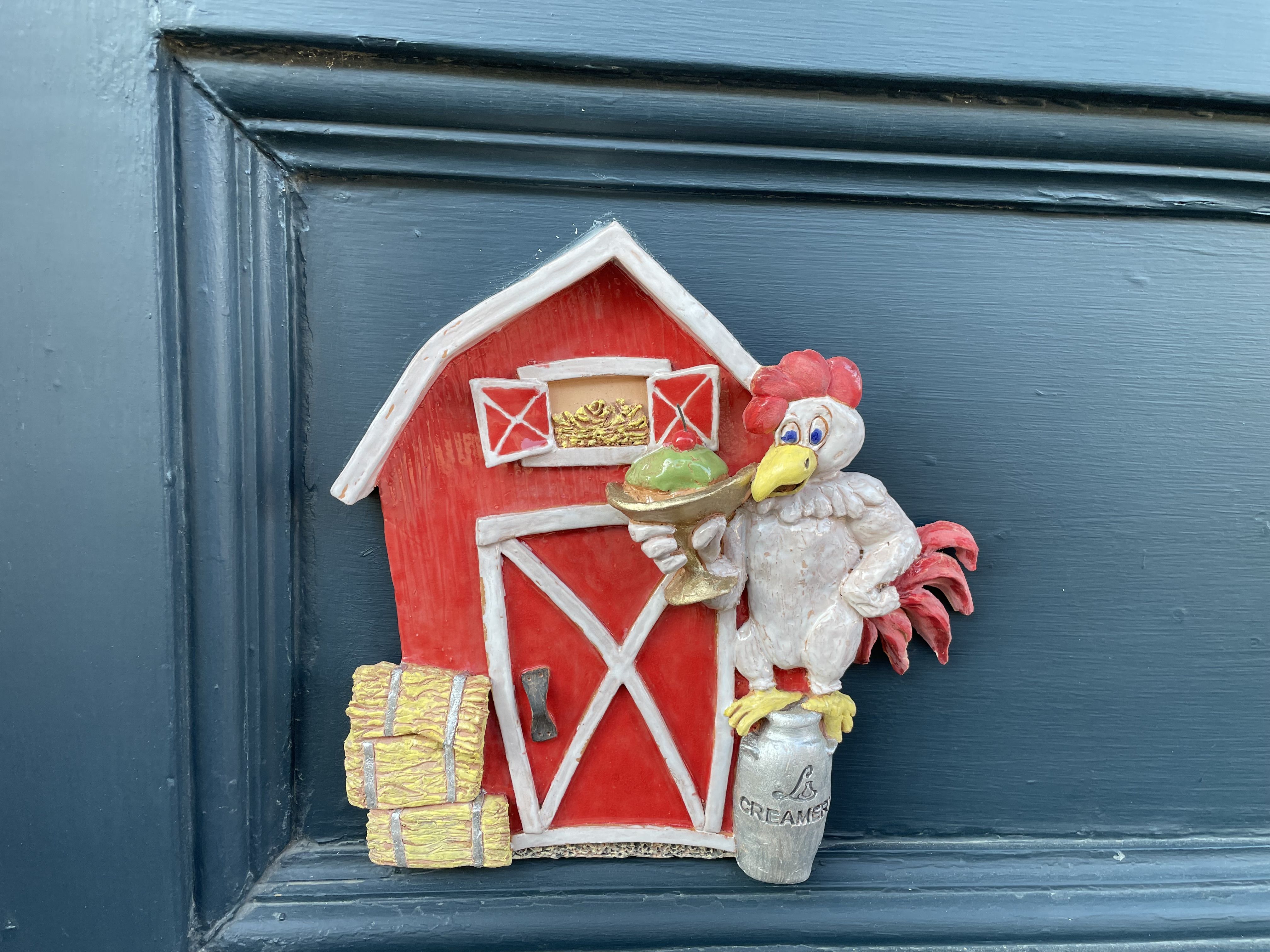 A tiny barn-style door and a tiny plaster chicken