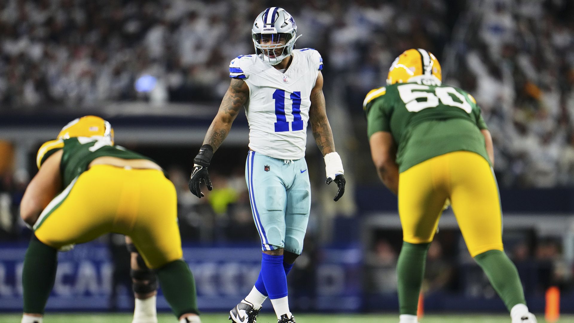 Micah Parsons stands between two Green Bay Packers players