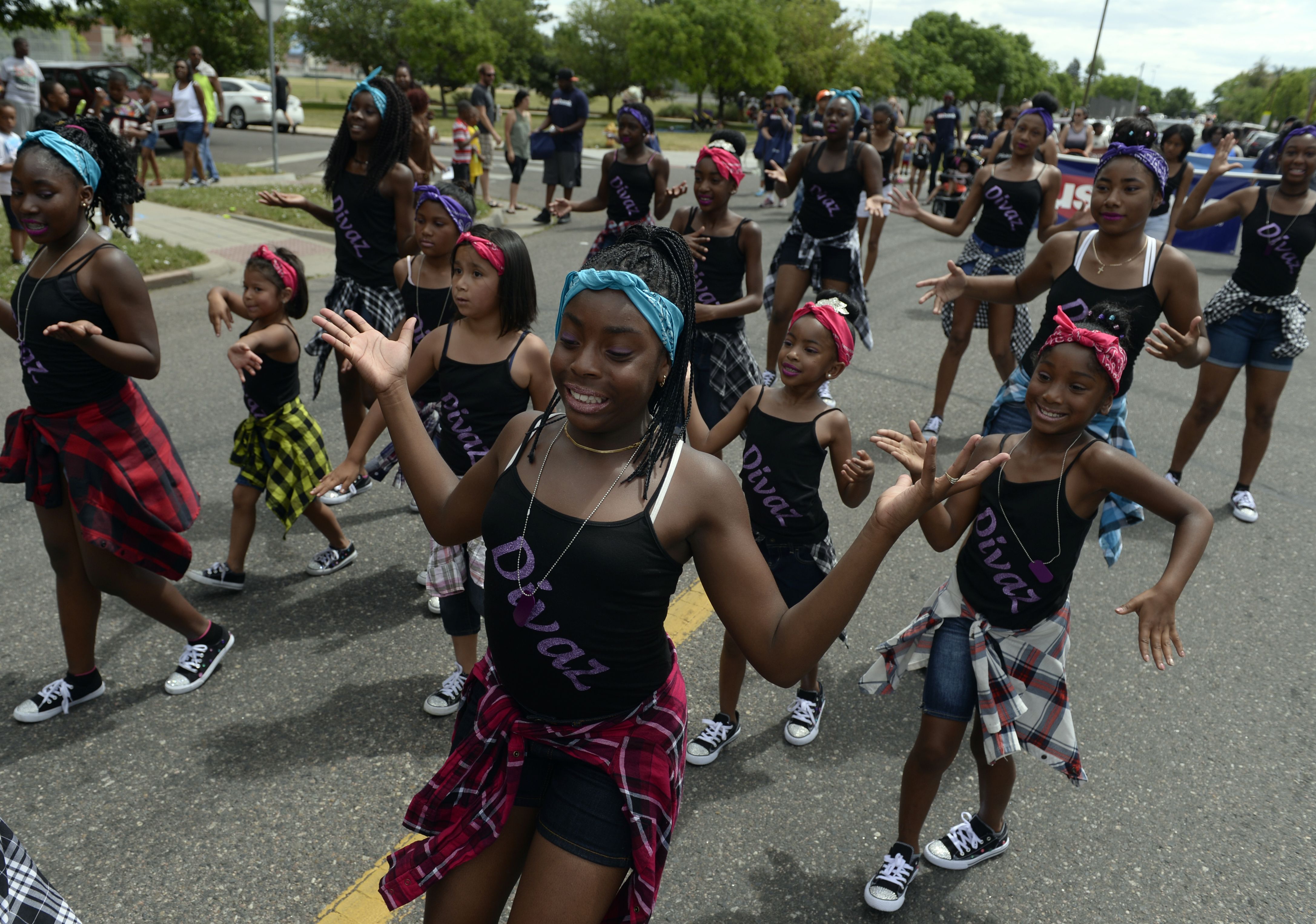 Girls dance in unison down a street.  