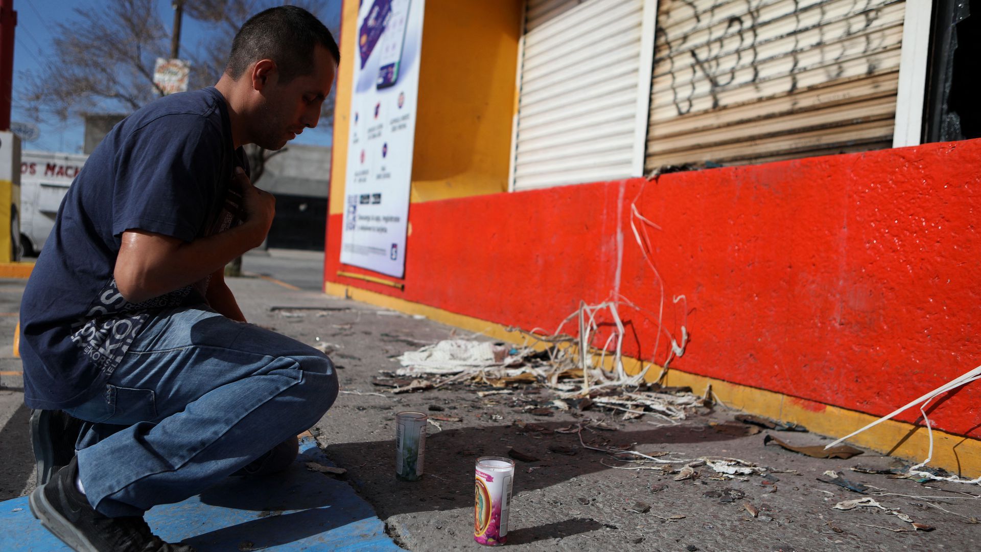 A man kneels next to a small memorial for murder victims in Ciudad Juarez, Mexico