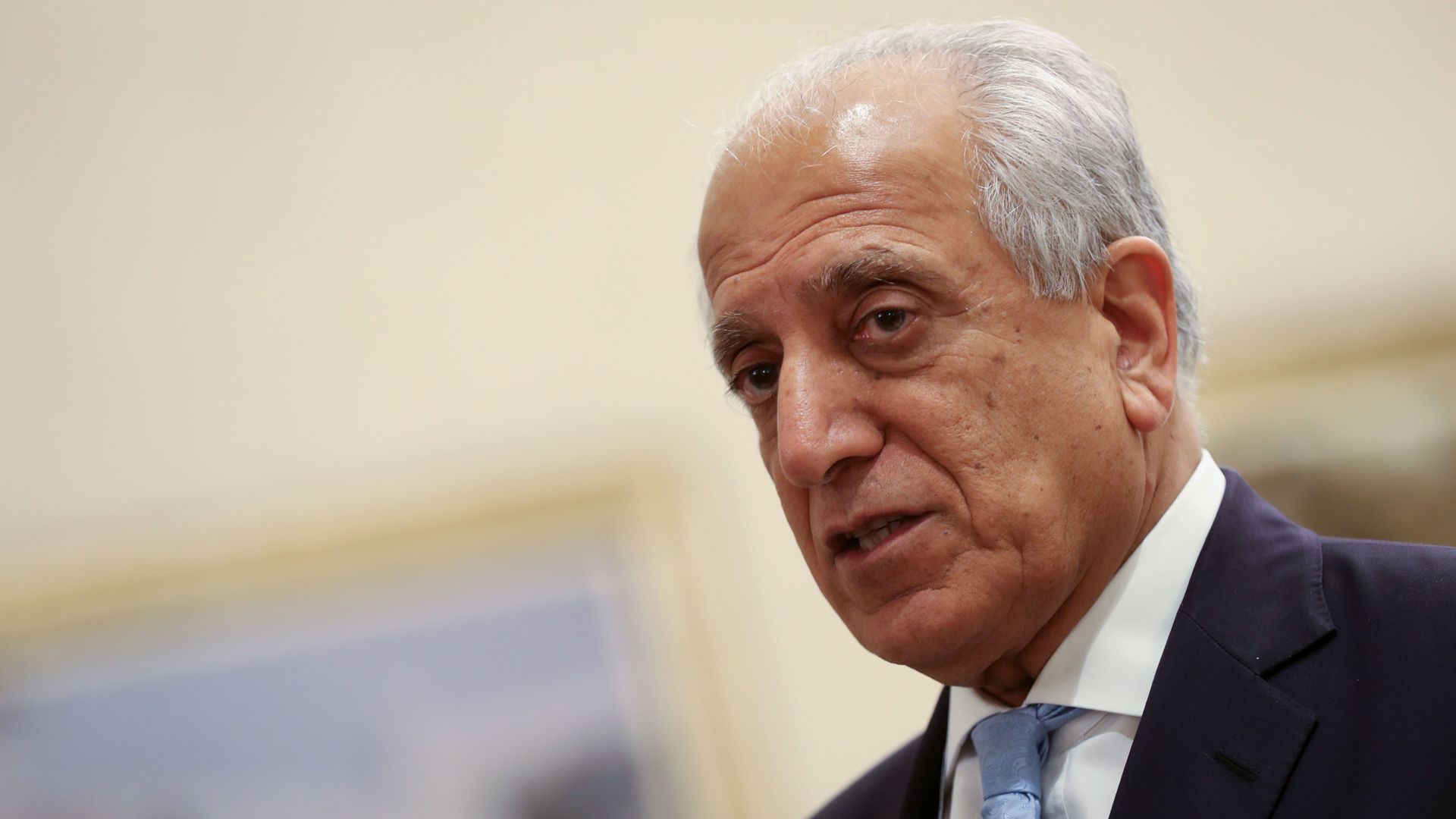 In this image, Khalilzad stands in a suit and tie