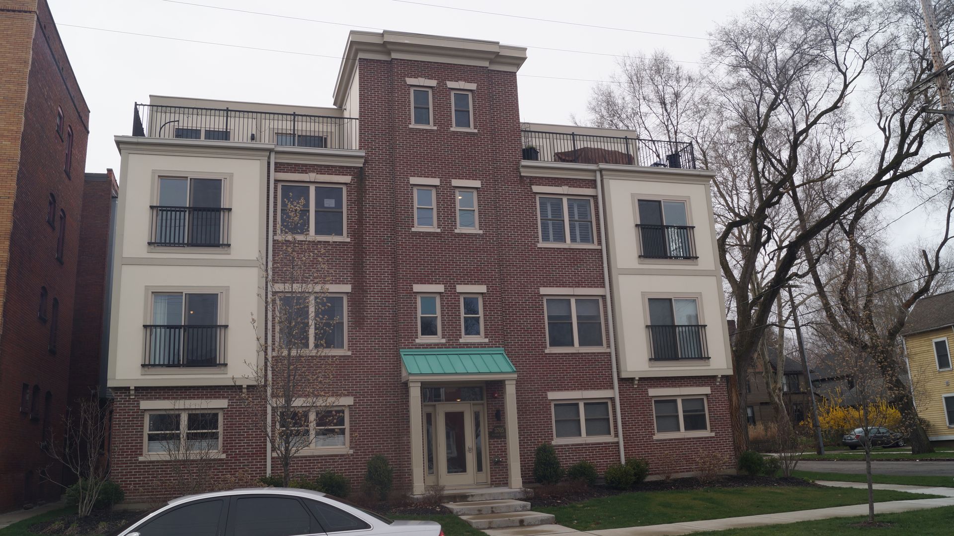 A brick condominium building on a residential street, overcast sky 