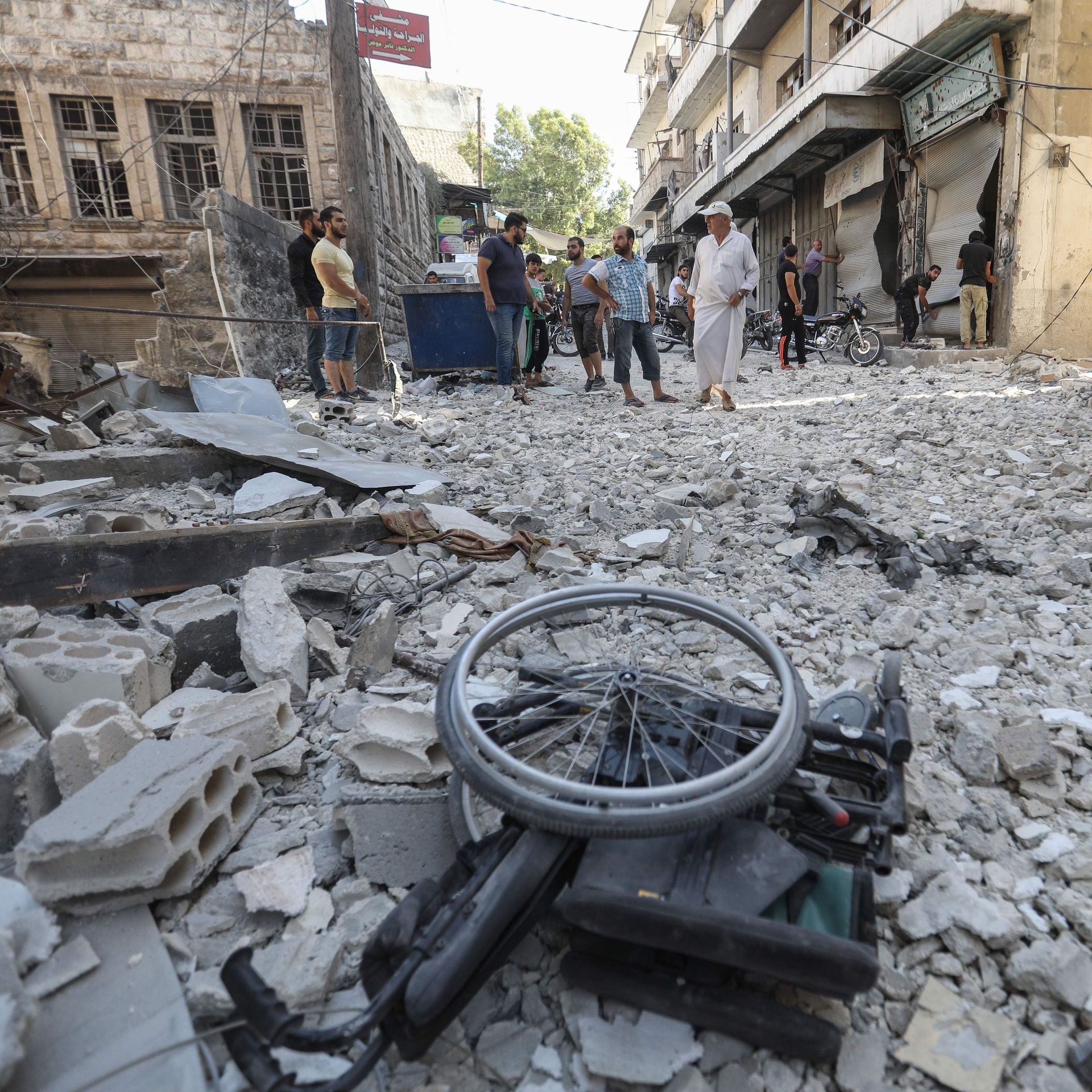 rubble of a building hit by an airstrike, with people standing in the background