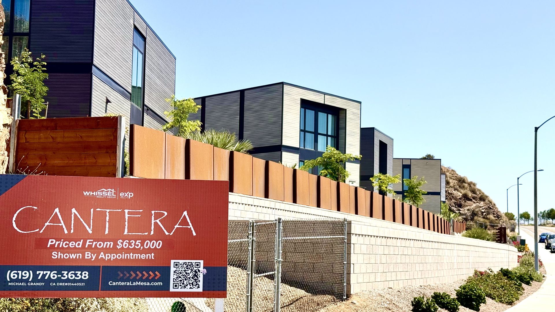 A housing project in a hillside with a sign out front that reads "Cantera: Priced from $635,000"