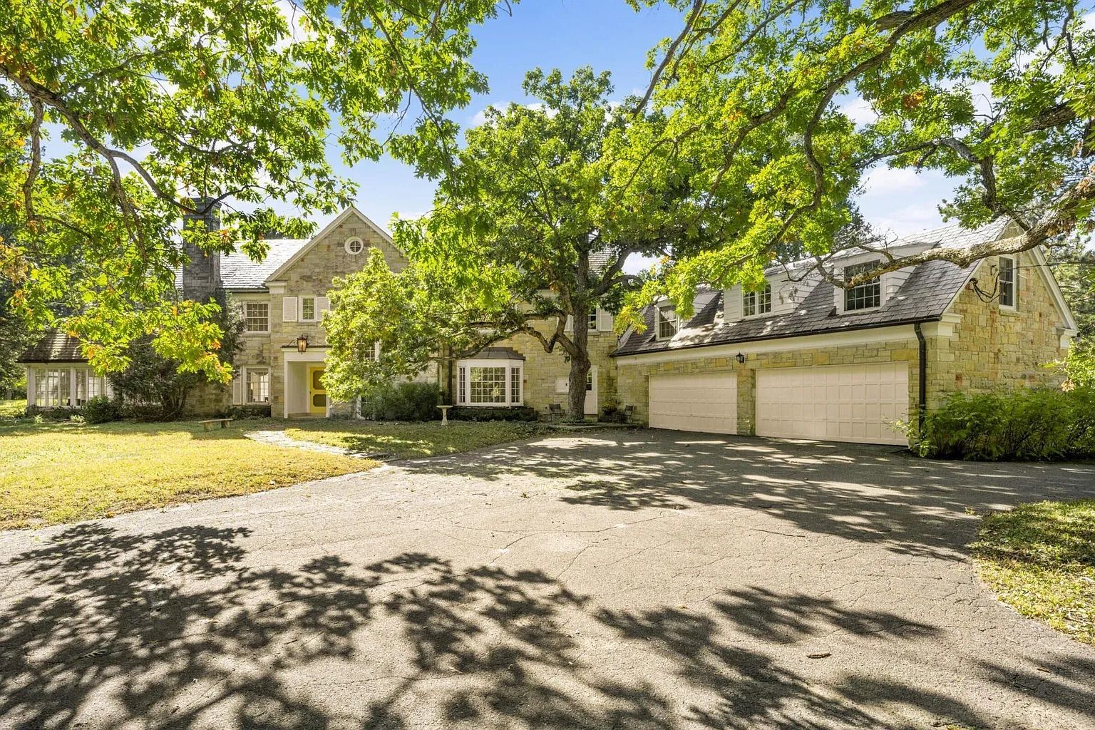 A large house made of tan stone in a forest.