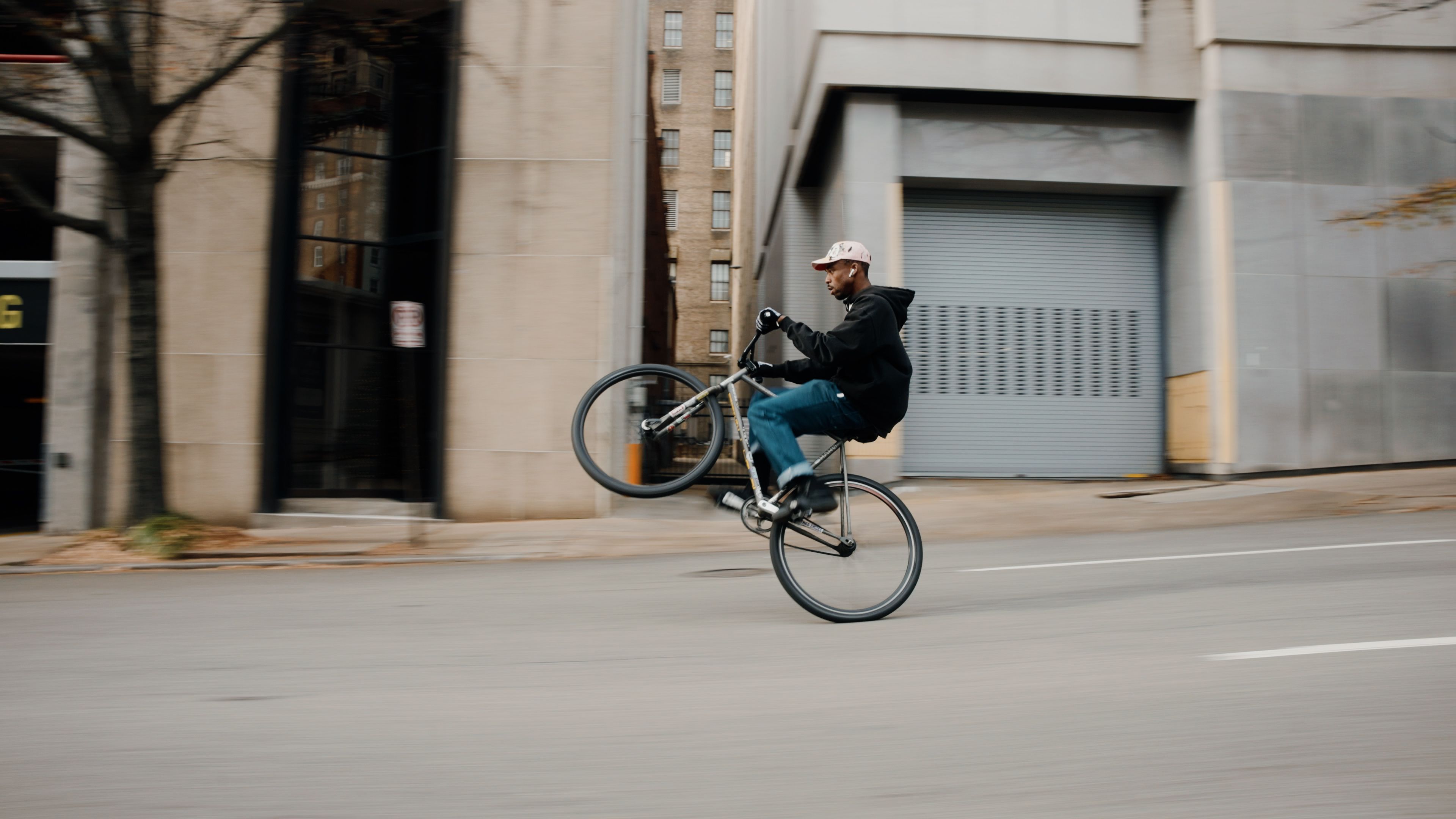 A picture of a man doing a wheelie on a bike down the street.