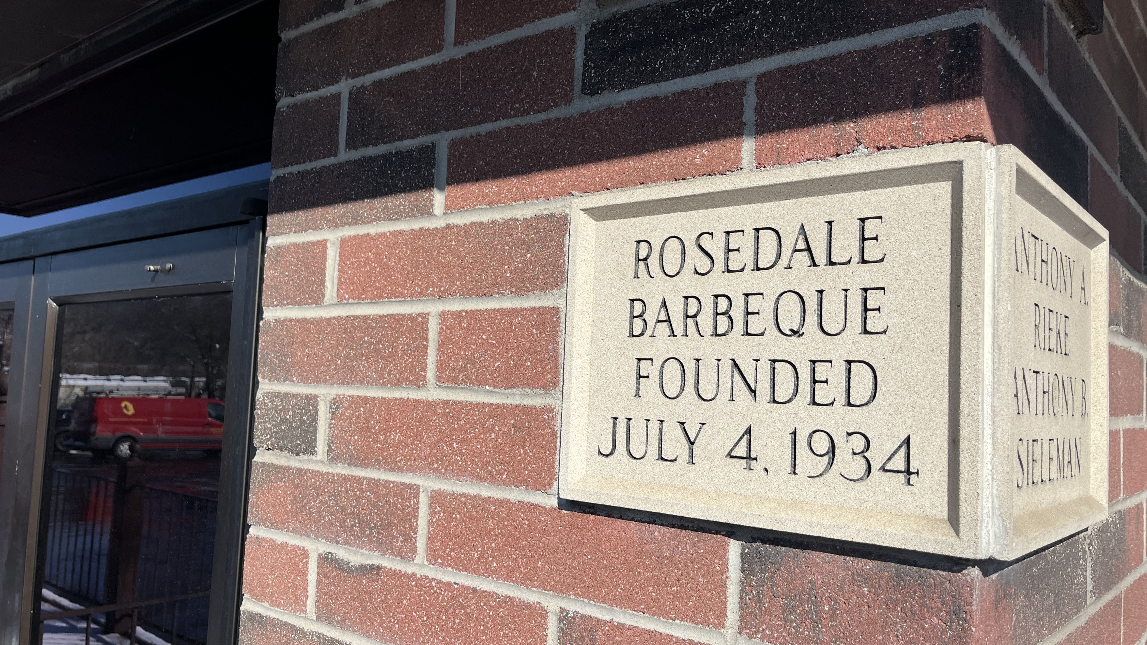 Corner brick wall with a stone plaque reading "Rosedale Barbeque Founded July 4, 1934" and names Anthony A. Rieke and Anthony B. Sieleman on the side.