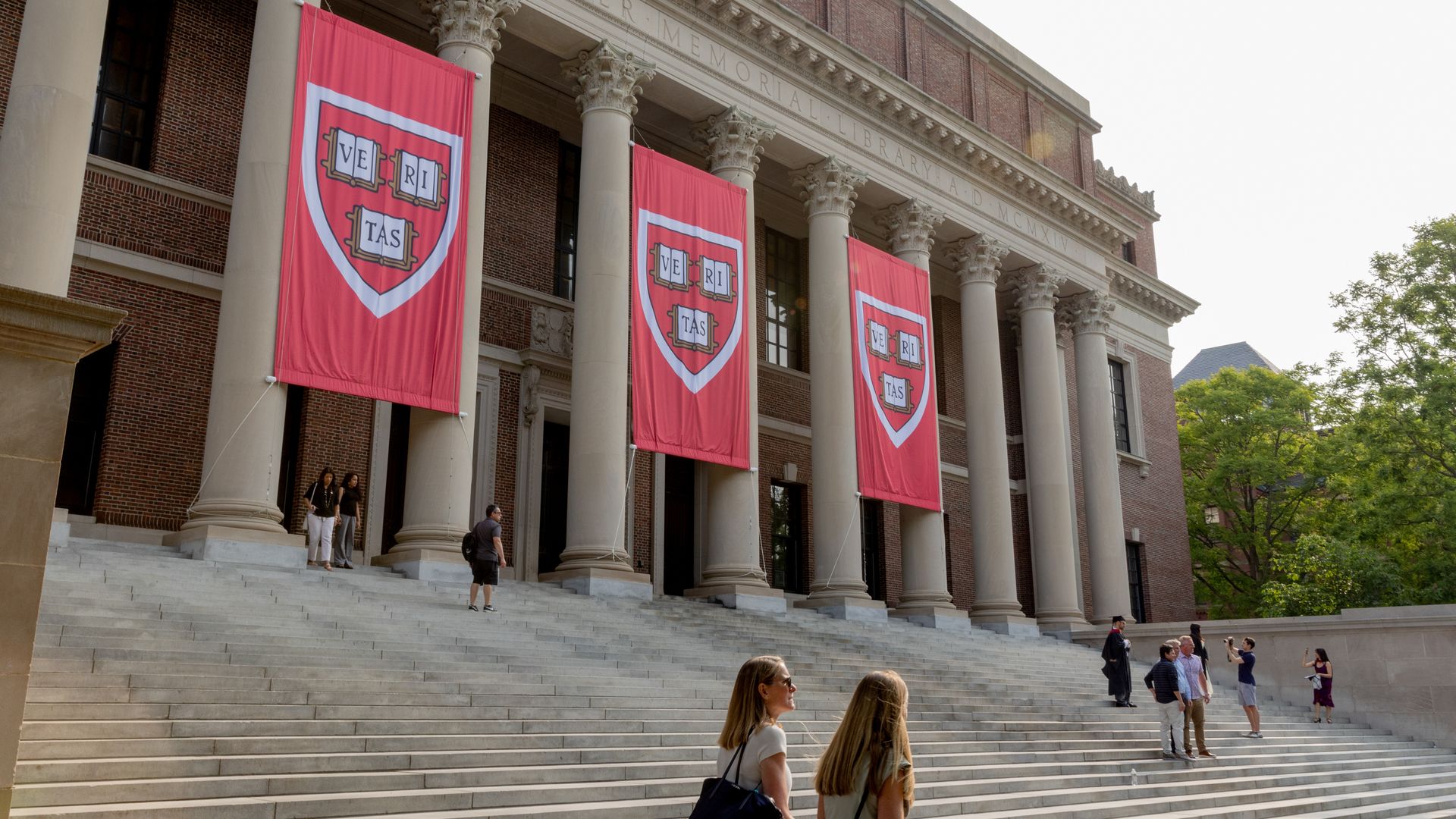Red banners hang between columns at a building on Harvard's campus.