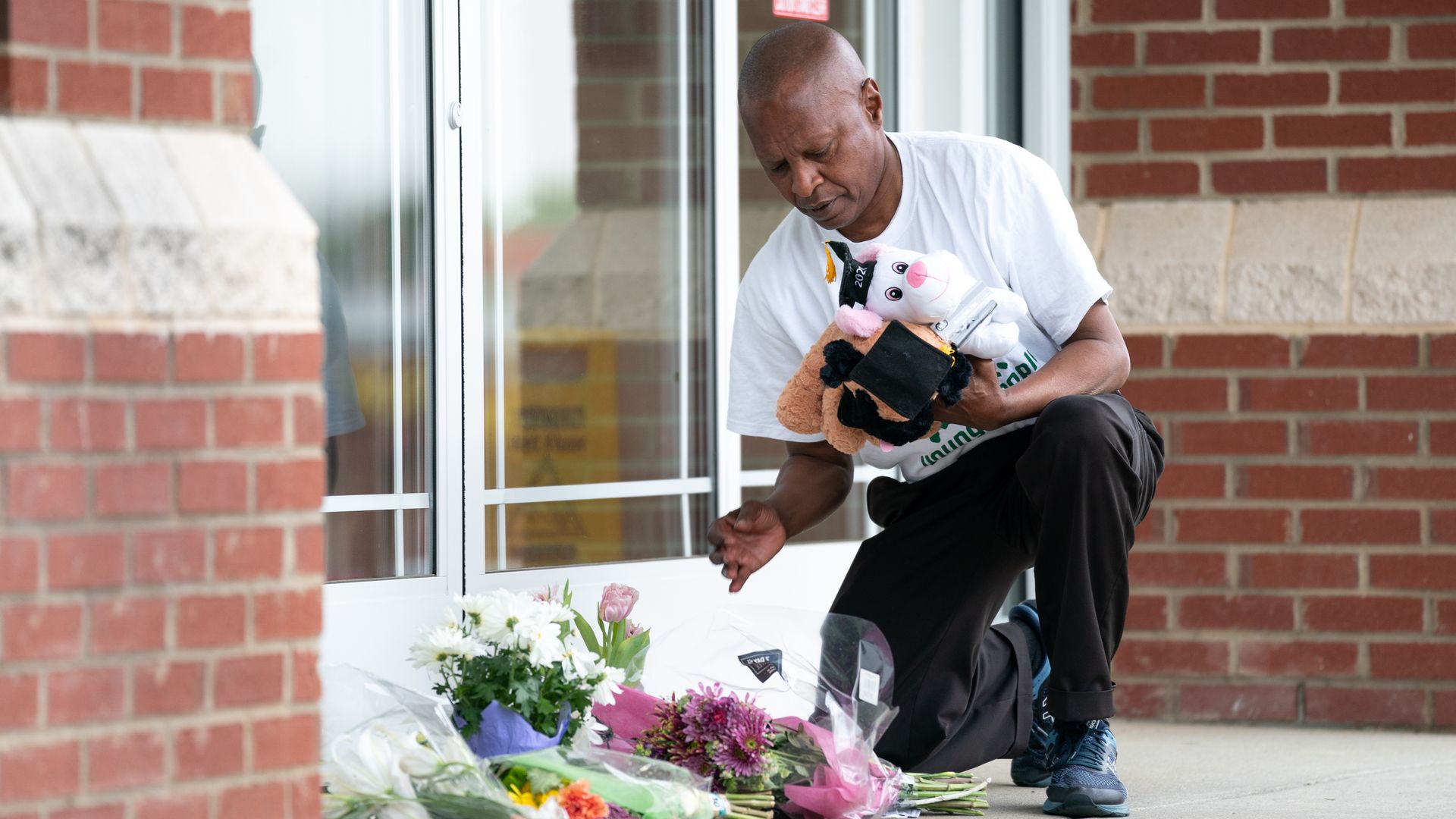 A man places stuffed animals and flowers outside of Riverview Family Medicine and Urgent Care after the fatal shooting of Dr. Robert Lesslie and four others the previous day on April 8