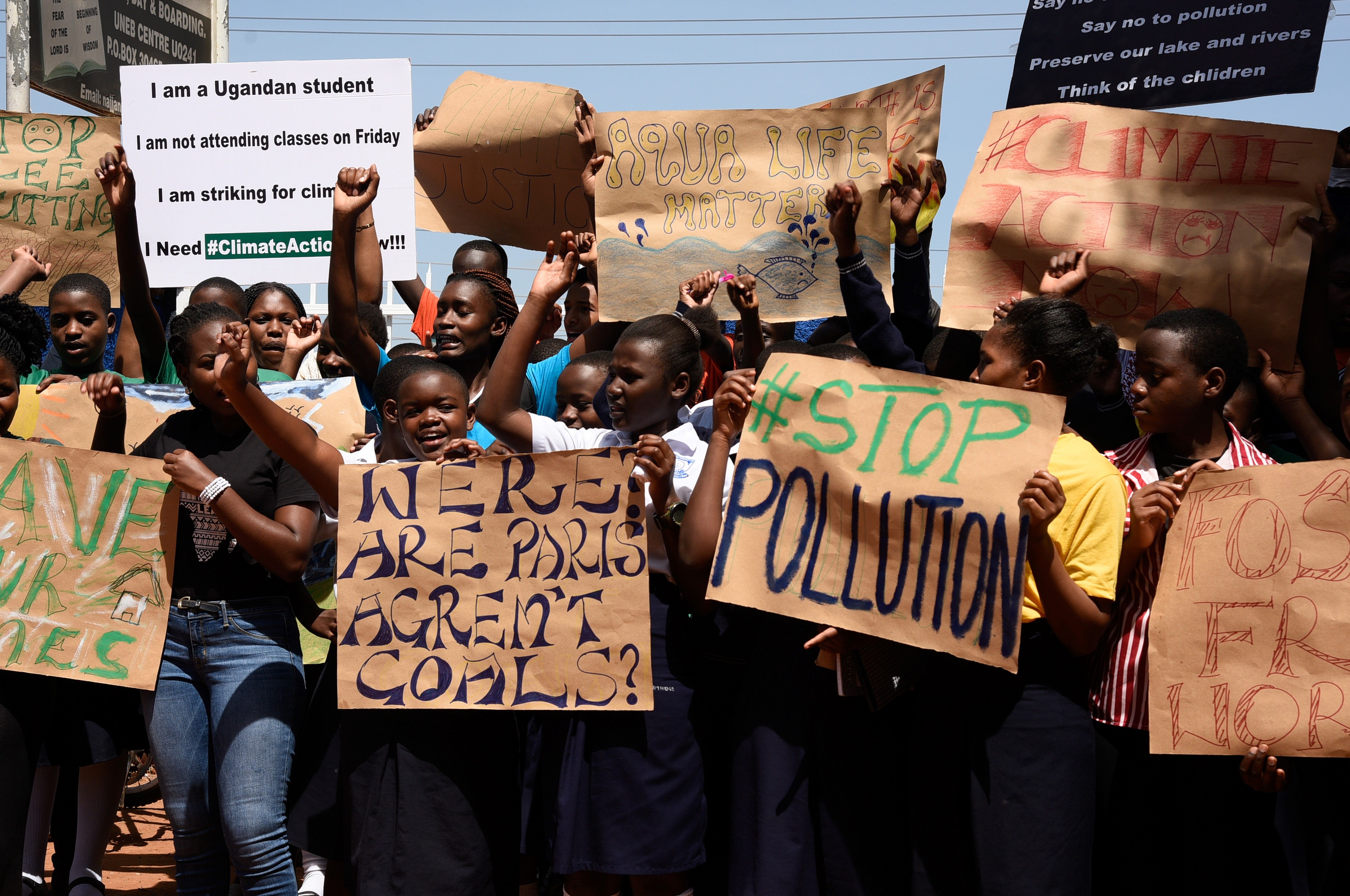 Ugandan students hold signs, one of which reads: "Stop Pollution"