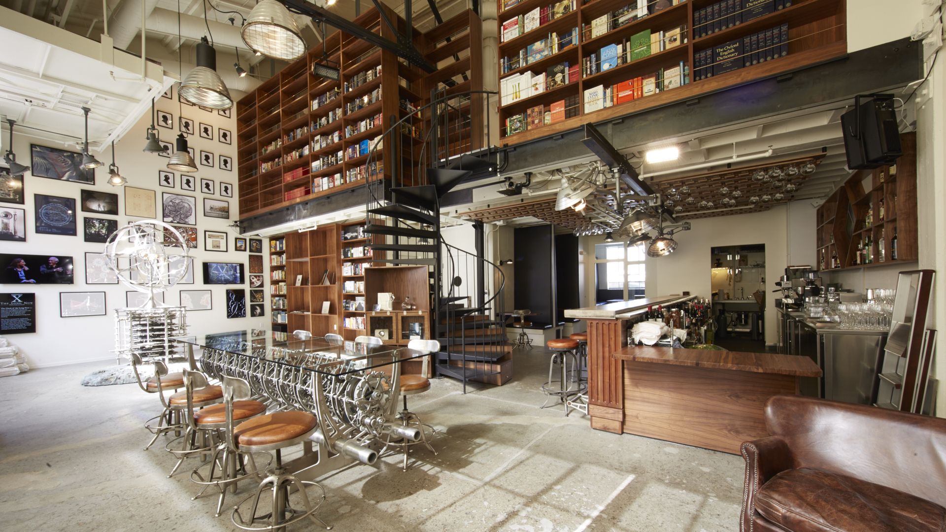 A photo of the interior of The Interval, featuring a mix of wood and metal furniture and floor-to-ceiling bookshelves.