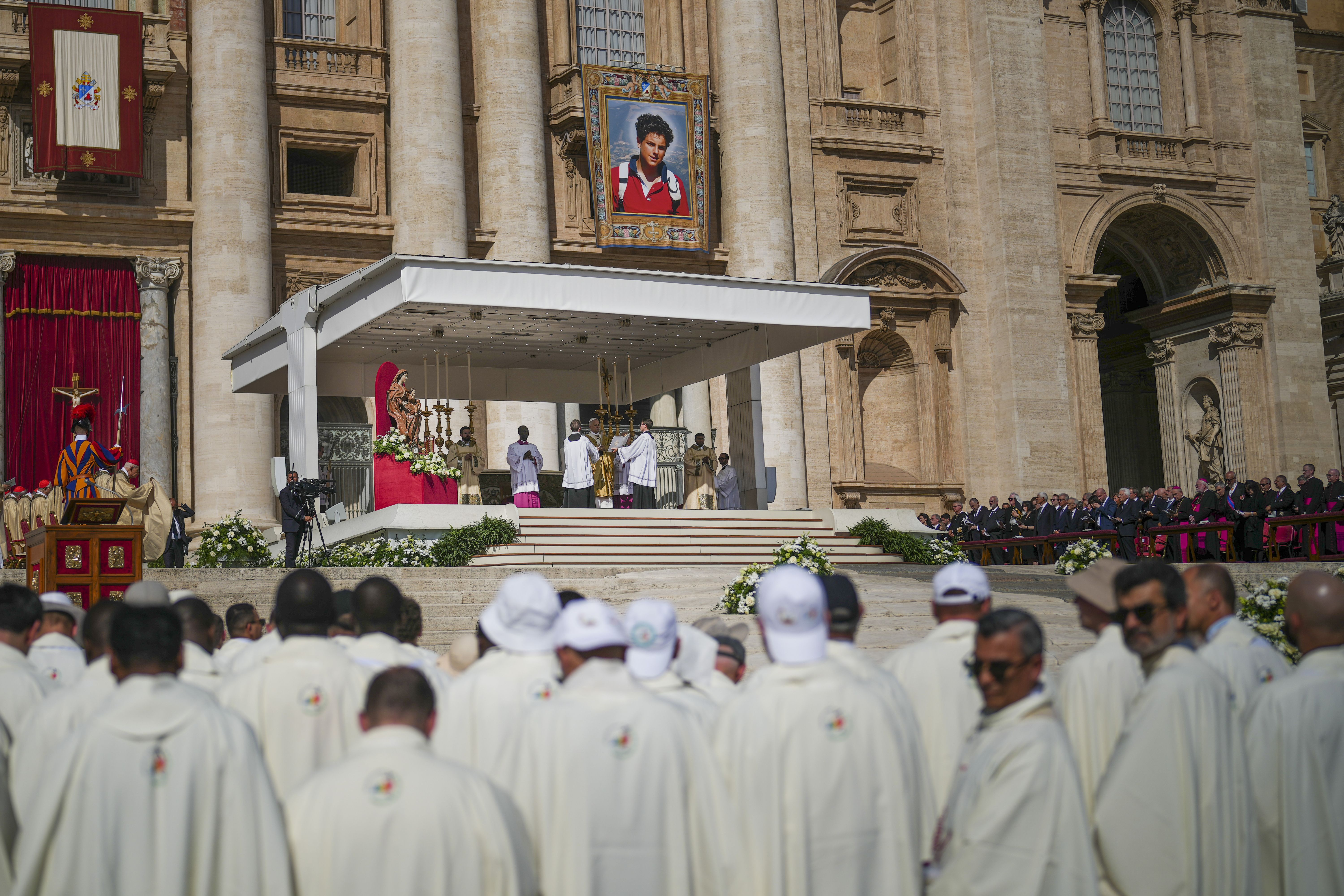 Pope Leo XIV during an open-air Mass in St. Peter's Square under a portrait of Carlo Acutis.