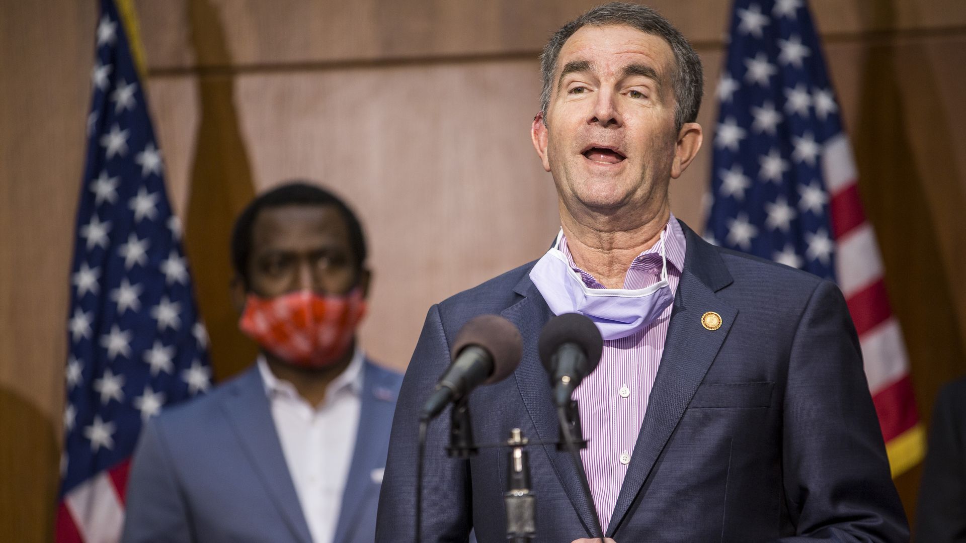 Virginia's governor stands in front of a podium with microphones 