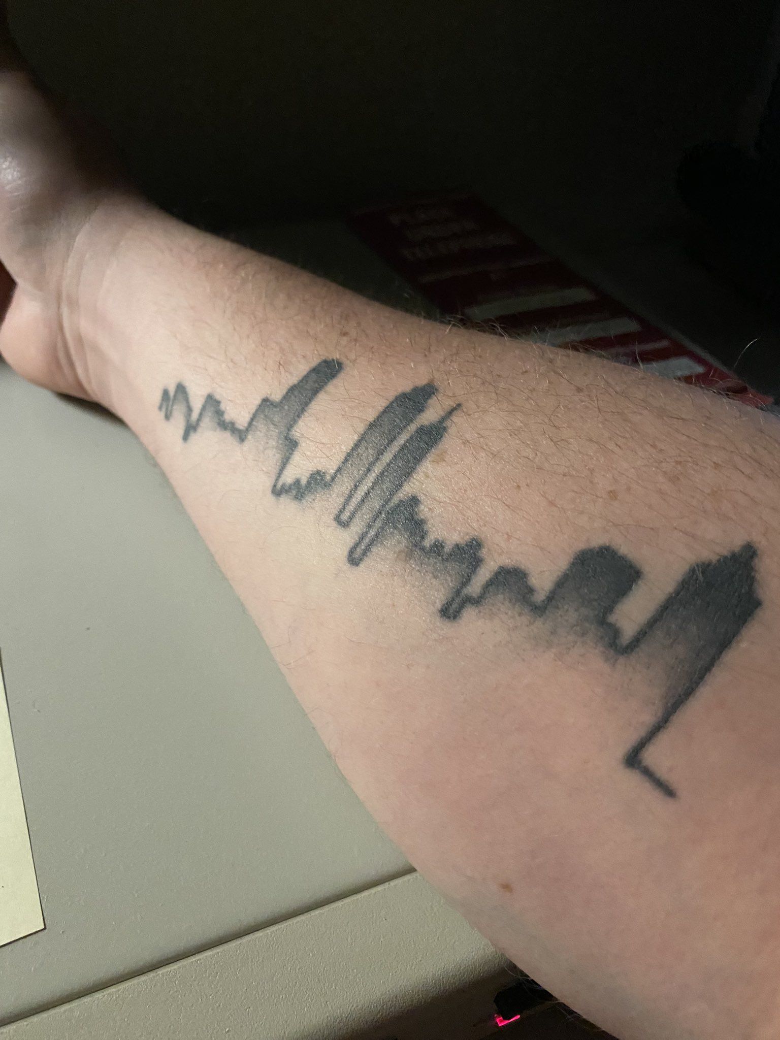 A tattoo of a silhouette of the Atlanta skyline on a person's forearm
