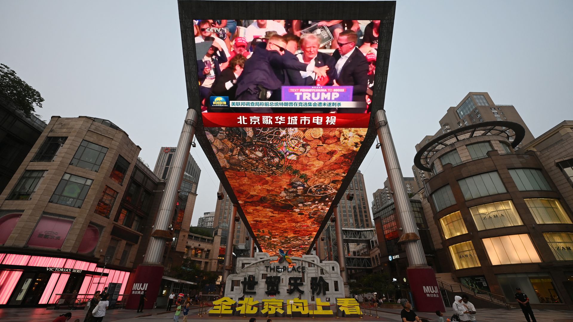A giant TV screen seen above a commercial area in China, showing news of the attack on former president Donald Trump.
