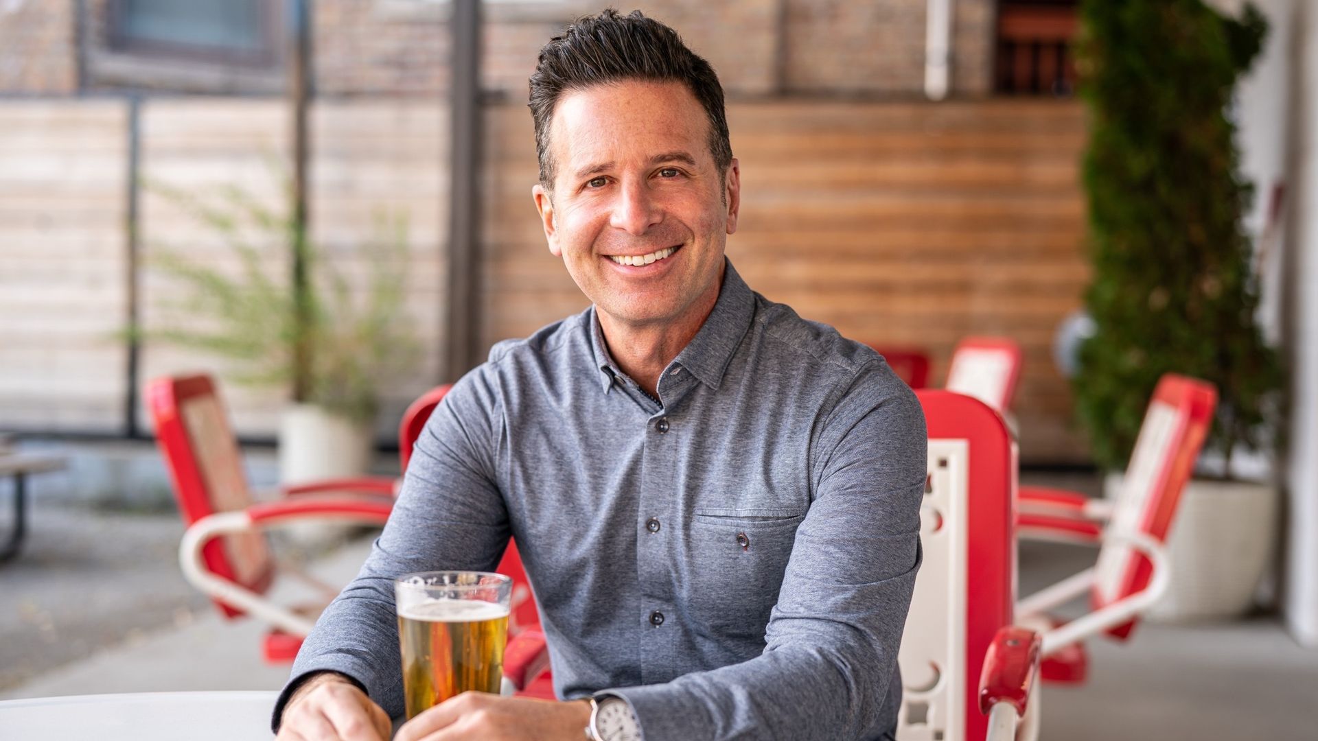 Photo of a man sitting at a table drinking a beer. 