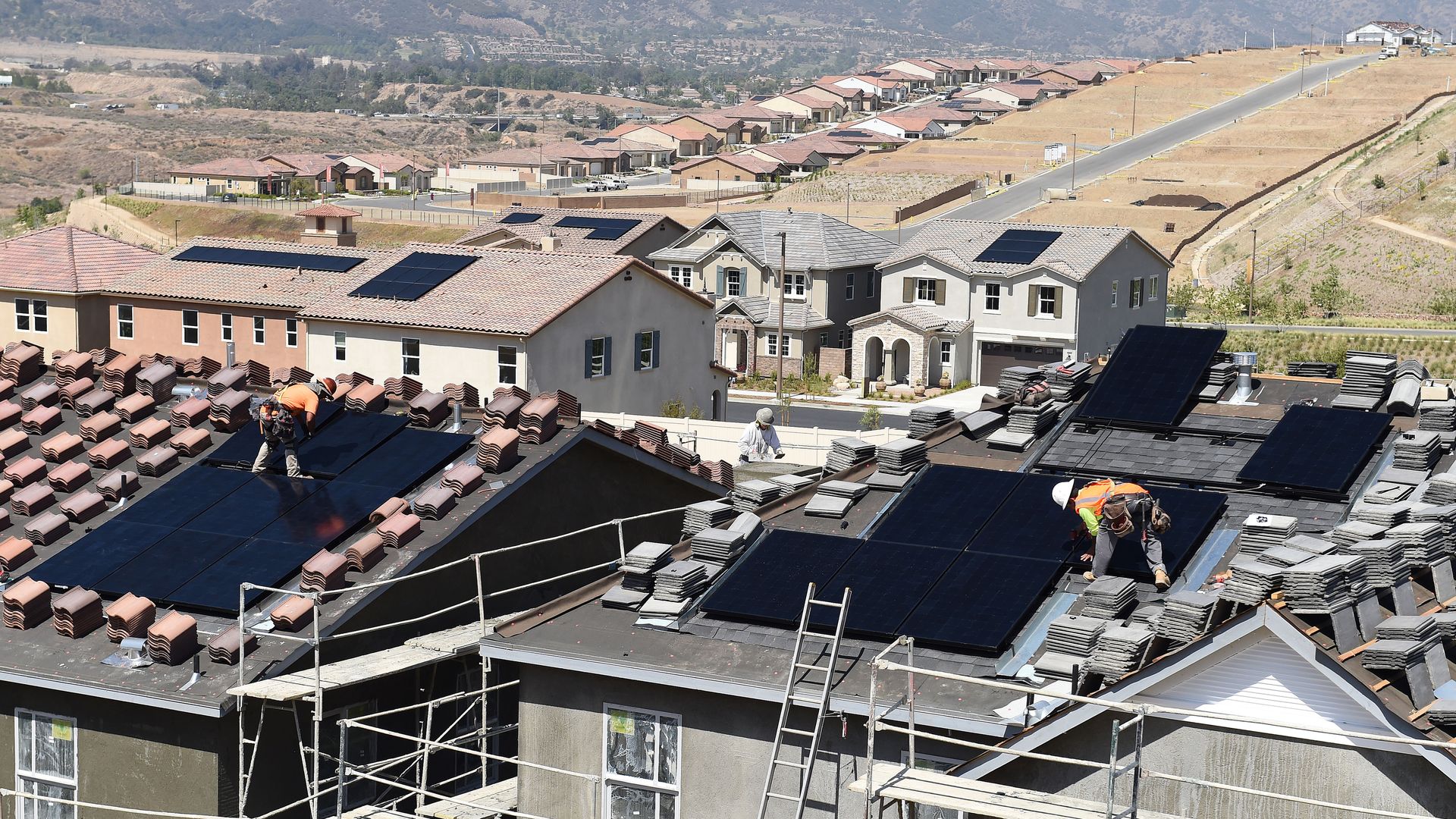 Workers install solar panels on the roofs of homes under construction south of Corona Thursday morning May 3, 2018. 