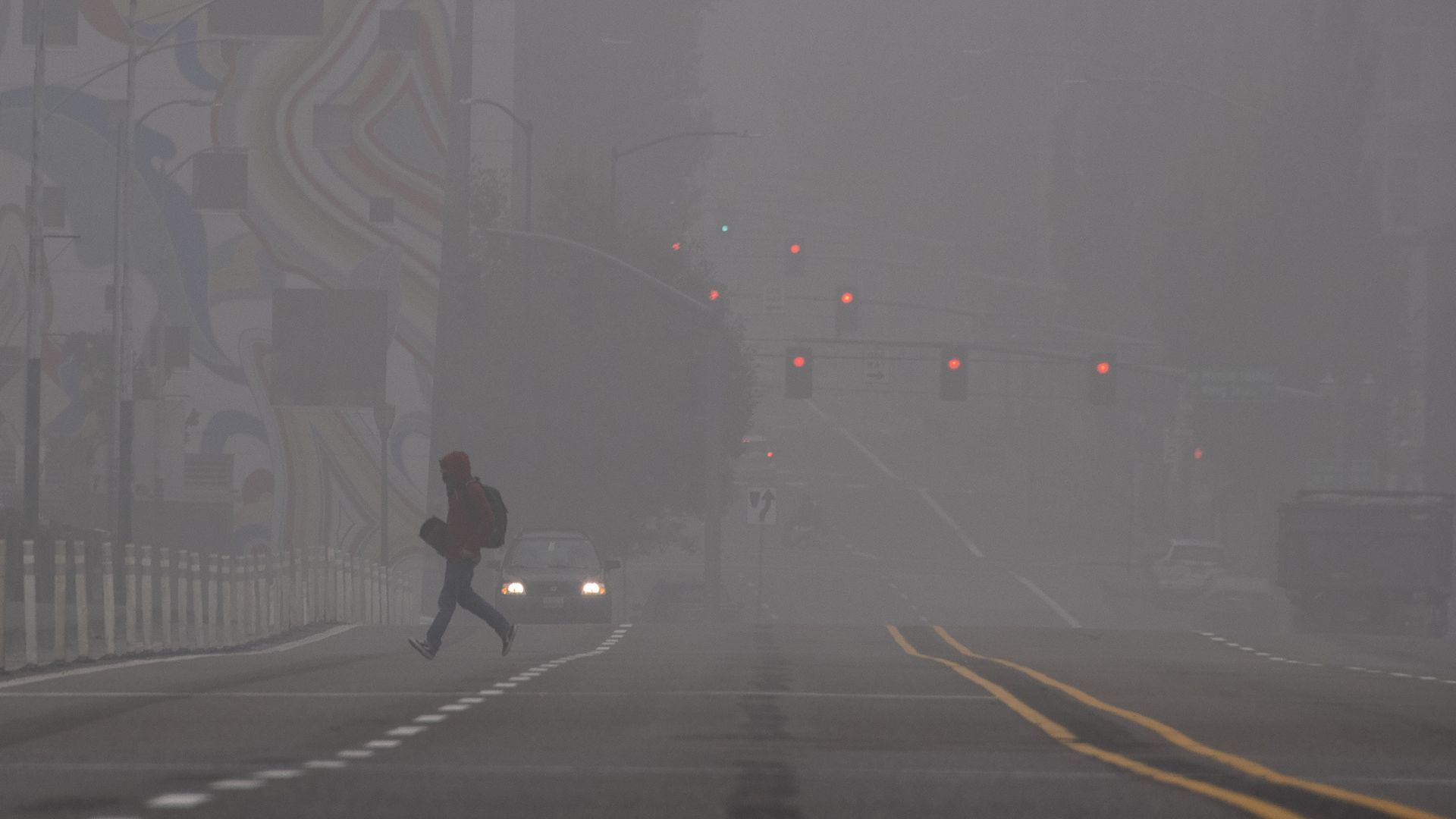 A pedestrian is seen walking through smoke. 