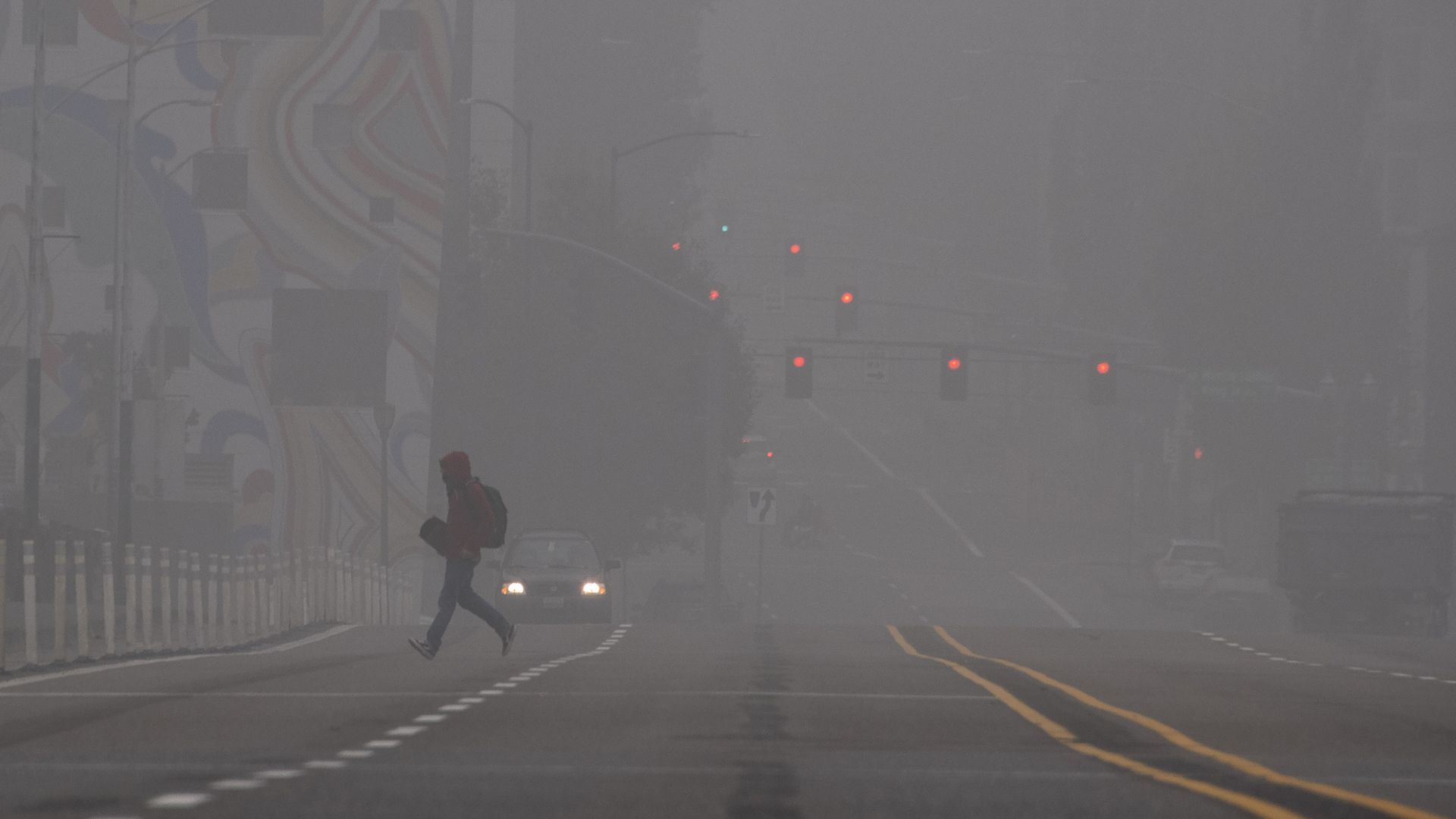 A pedestrian is seen walking through smoke.