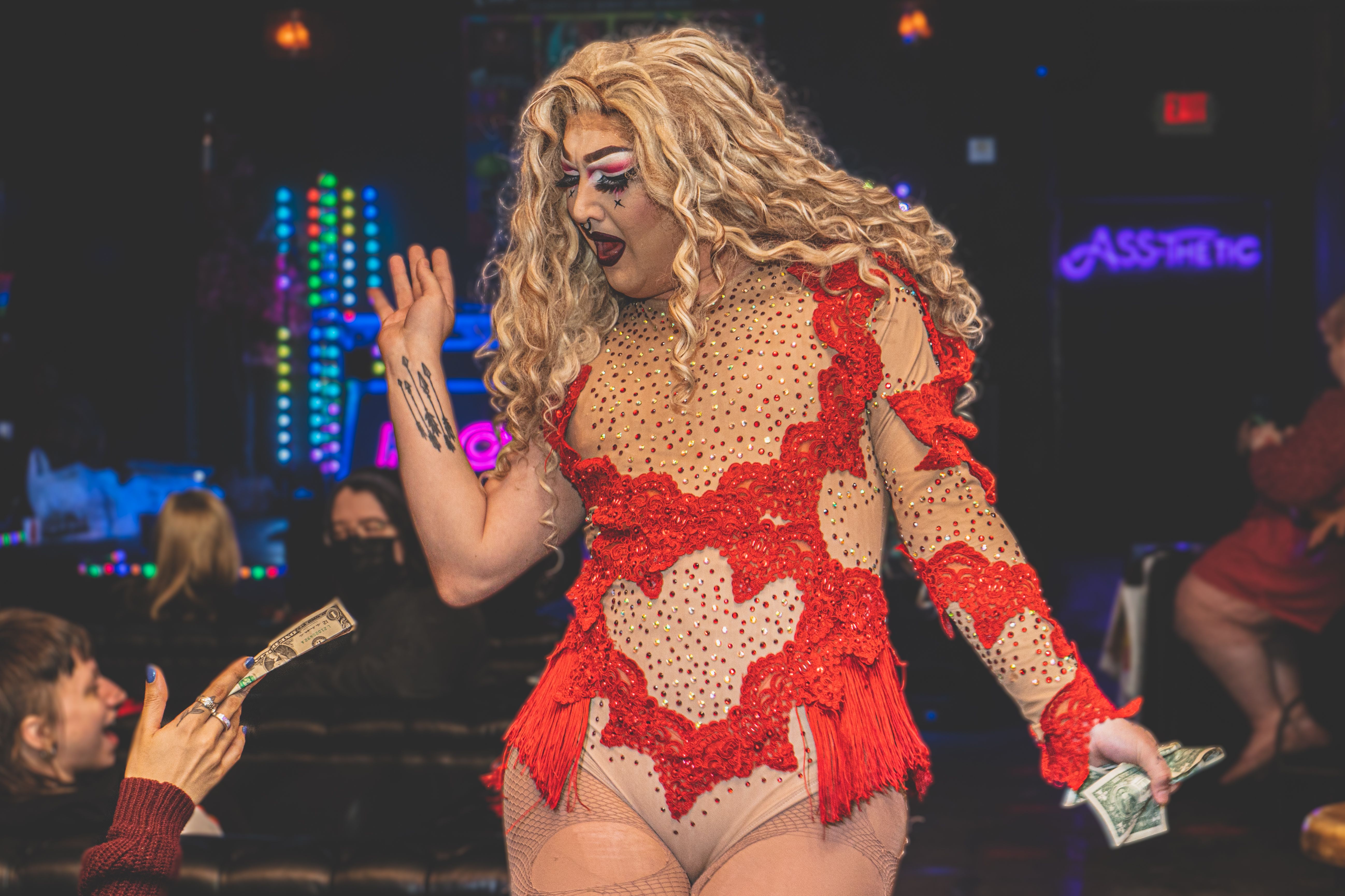 Photo of a drag queen wearing a red leotard. 