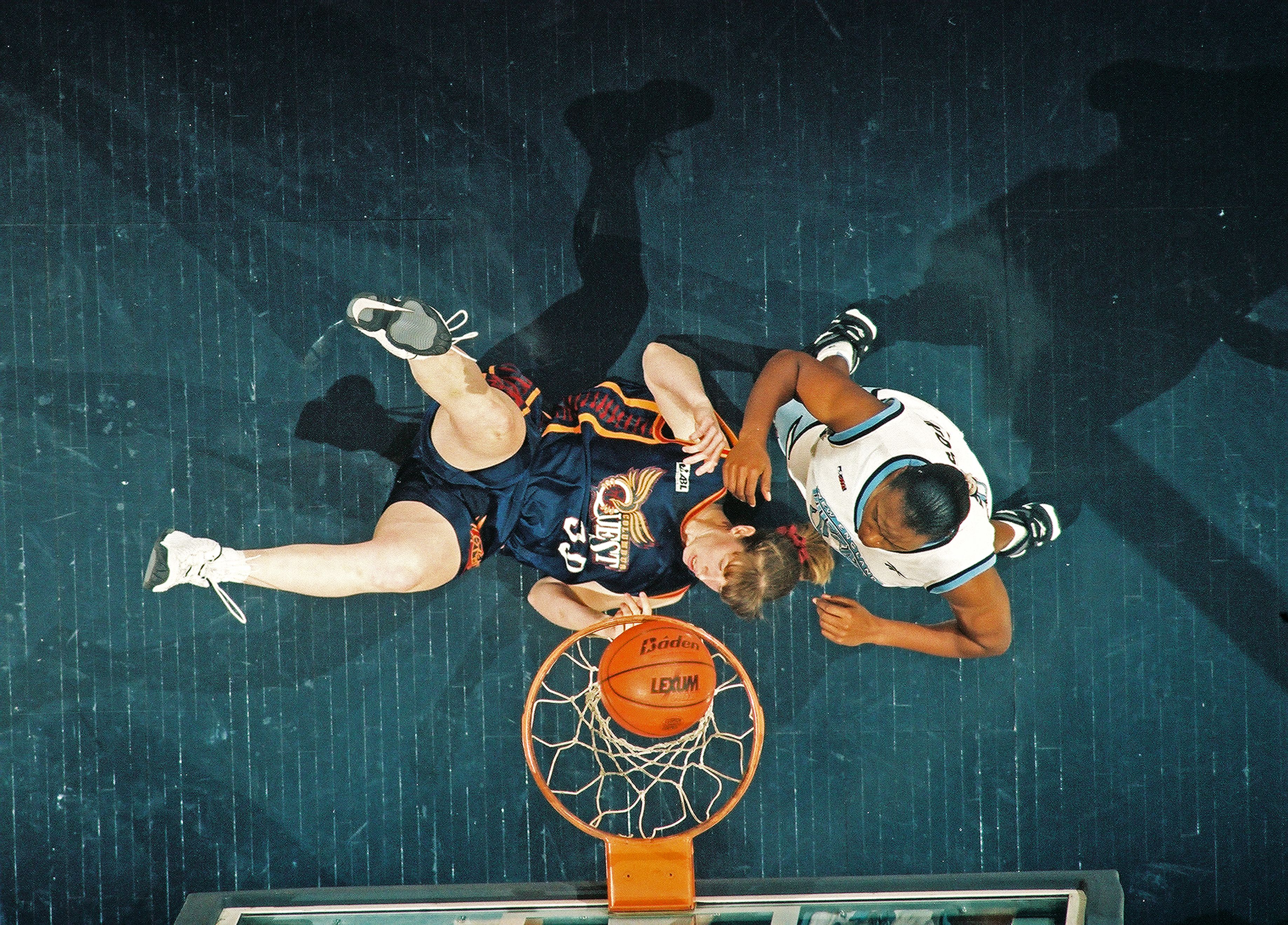 An overhead view of a Columbus Quest player shooting a basketball against a New England Blizzard defender. 